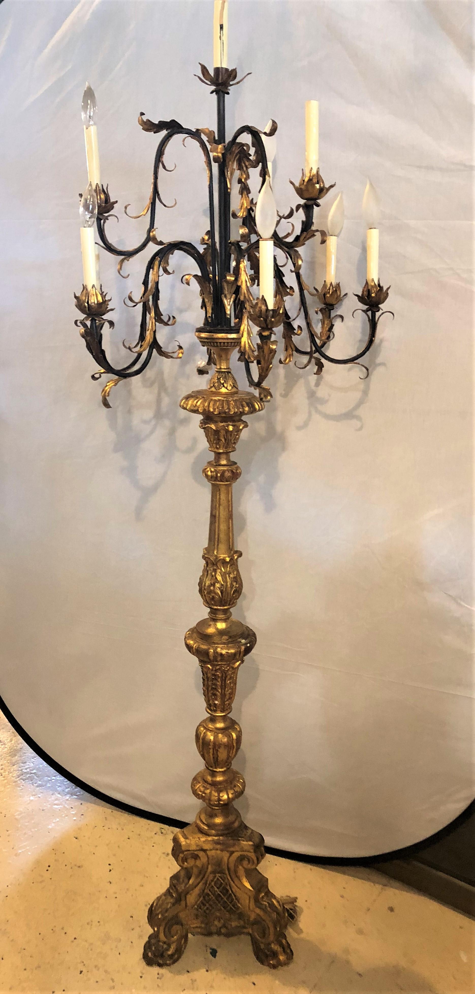 An Italian ten-light giltwood and iron torchiere. This fantastic antique standing light has a wonderfully warm worn gilt gold finish over clay. The tri legged base supporting a center column-form single pedestal having multiple flowing arms with ten