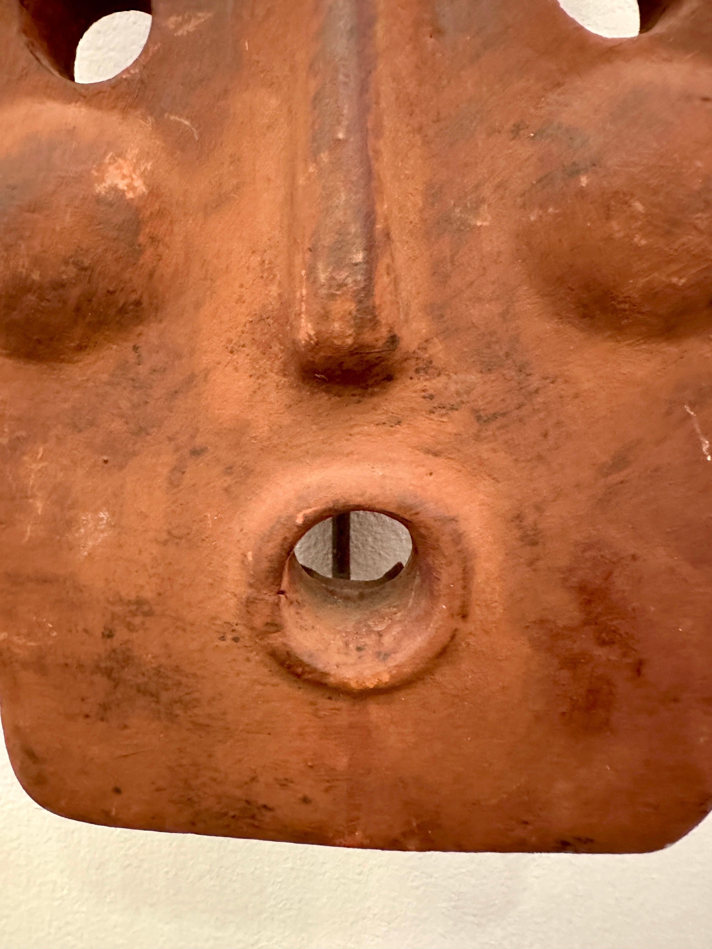 Primitive style sculptural clay mask candle sconce made in Italy. Hand made in an aged adobe color with a place for a single candle inside. Mask has a metal frame which gives the piece a nice depth from the wall and provides a surface for the candle