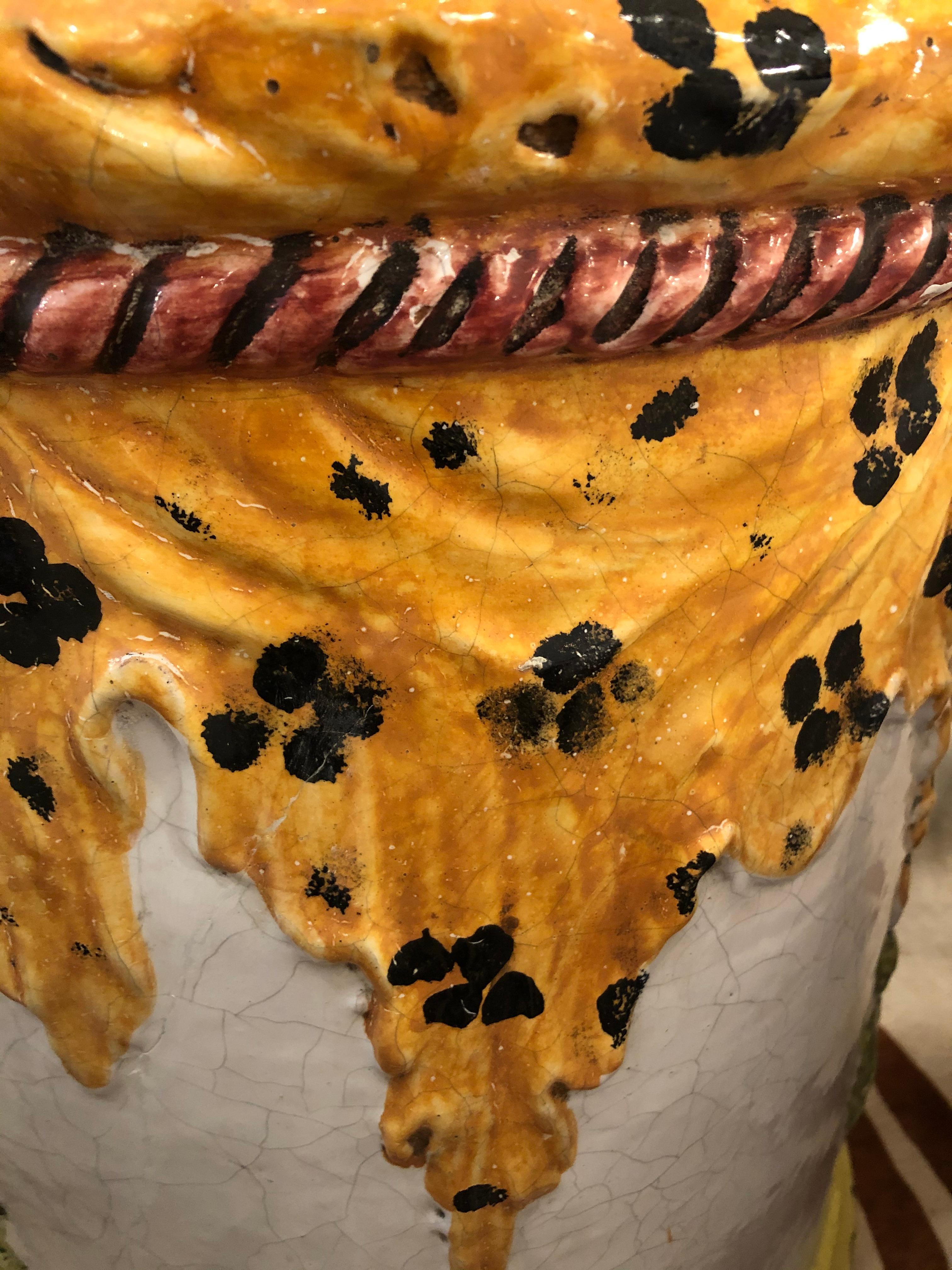 Une table ronde fantaisiste en terre cuite italienne pour le jardin, peinte de manière élégante avec un motif léopard sur le dessus et des glands sur le pourtour.