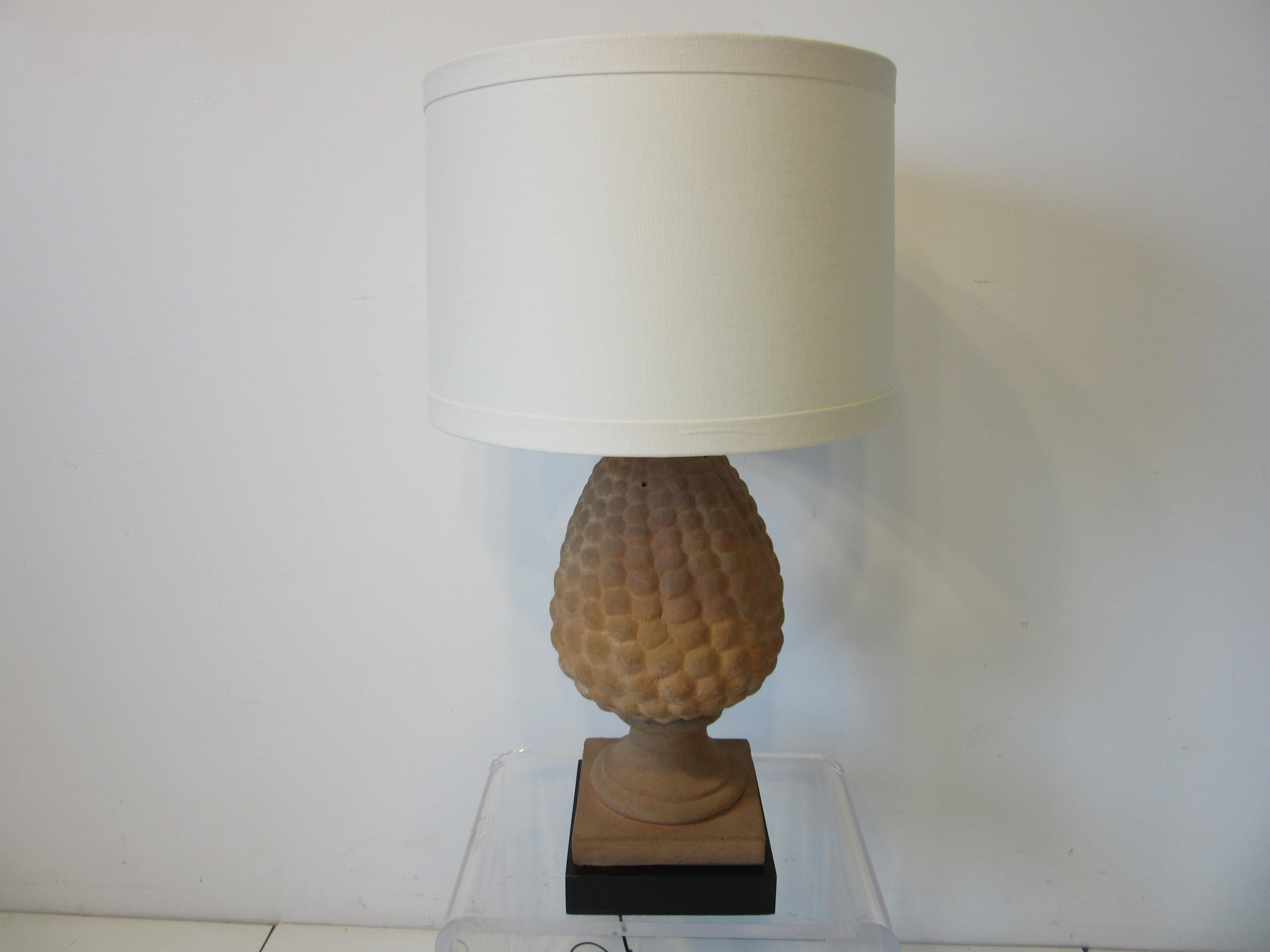 A mid century table lamp in Terracotta using the same methods as constructing baked roofing tiles, handcrafted in Italy mounted on a satin black wood base. Topped with a cream colored linen shade, signed and imprinted to the backside by the