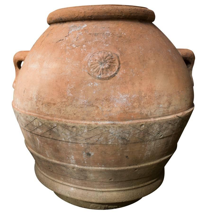 Large Italian terracotta urn with embossed flower insignia, detailed handles, decorative etchings and original drainage spout. The beautiful reddish terracotta commonly found in Italian antique pottery has patina but is also in superb condition for