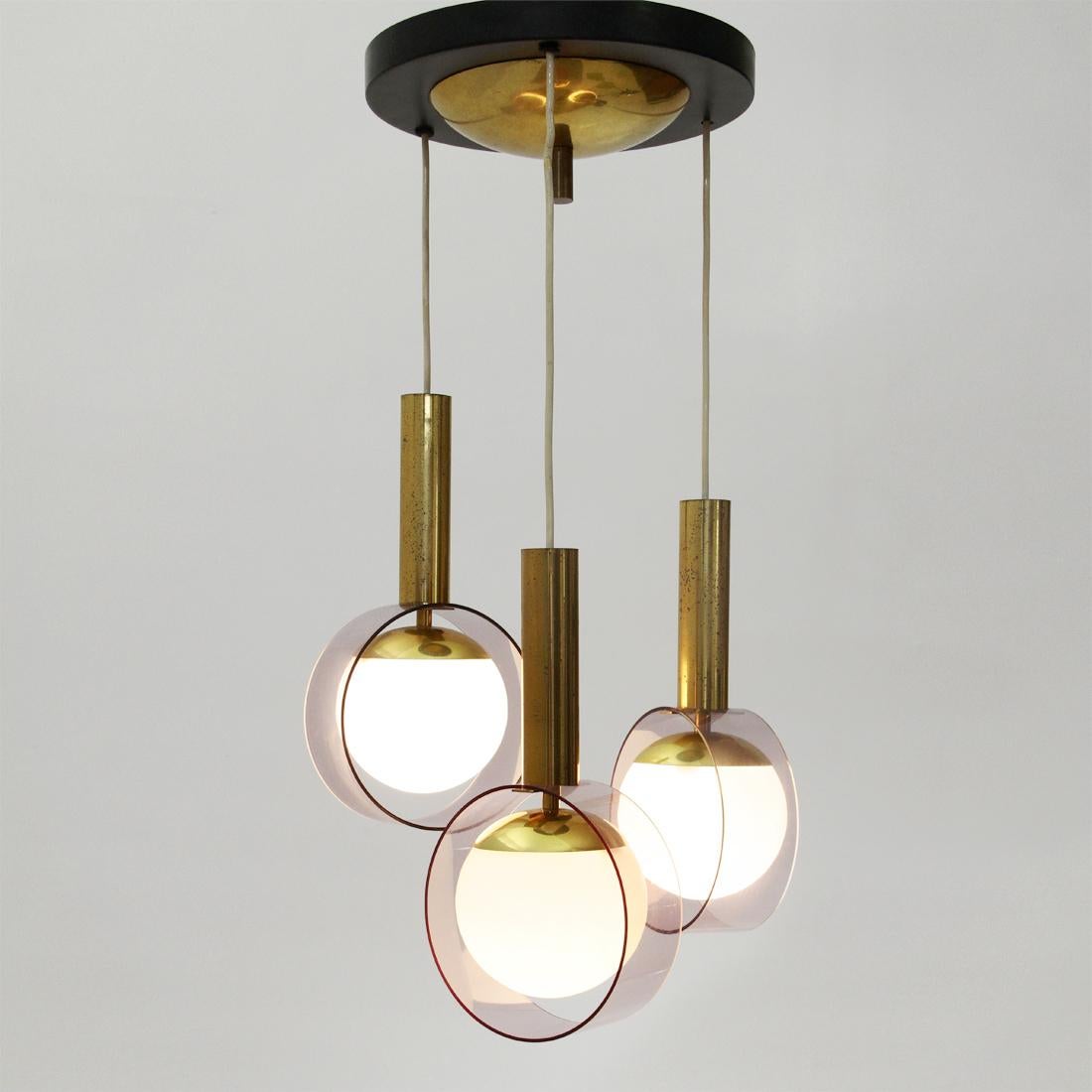 Chandelier produced by Stilux in the 1960s.
Rosette in black painted metal and brass.
Three pendants at different heights with brass frame and spherical diffusers in opal glass and pink perspex.
Good general conditions, some signs due to normal