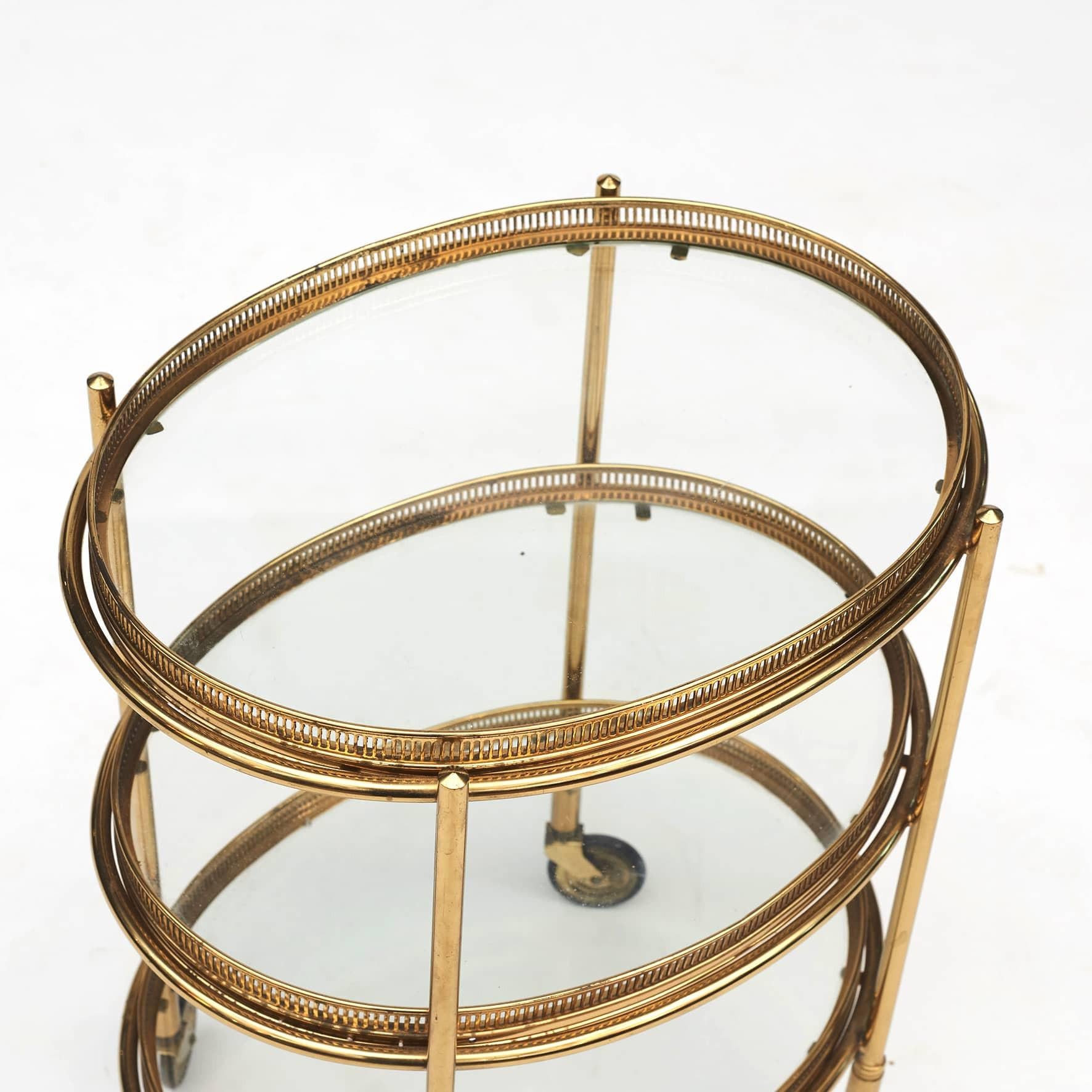Italian three tier bar cart / étagère made of brass with glass trays.
Three removable trays with clear glass center and pierced brass gallery rails. Brass and black rubber wheels.
In the style of Maison Jansen. Italy c. 1950.

Perfect condition.
