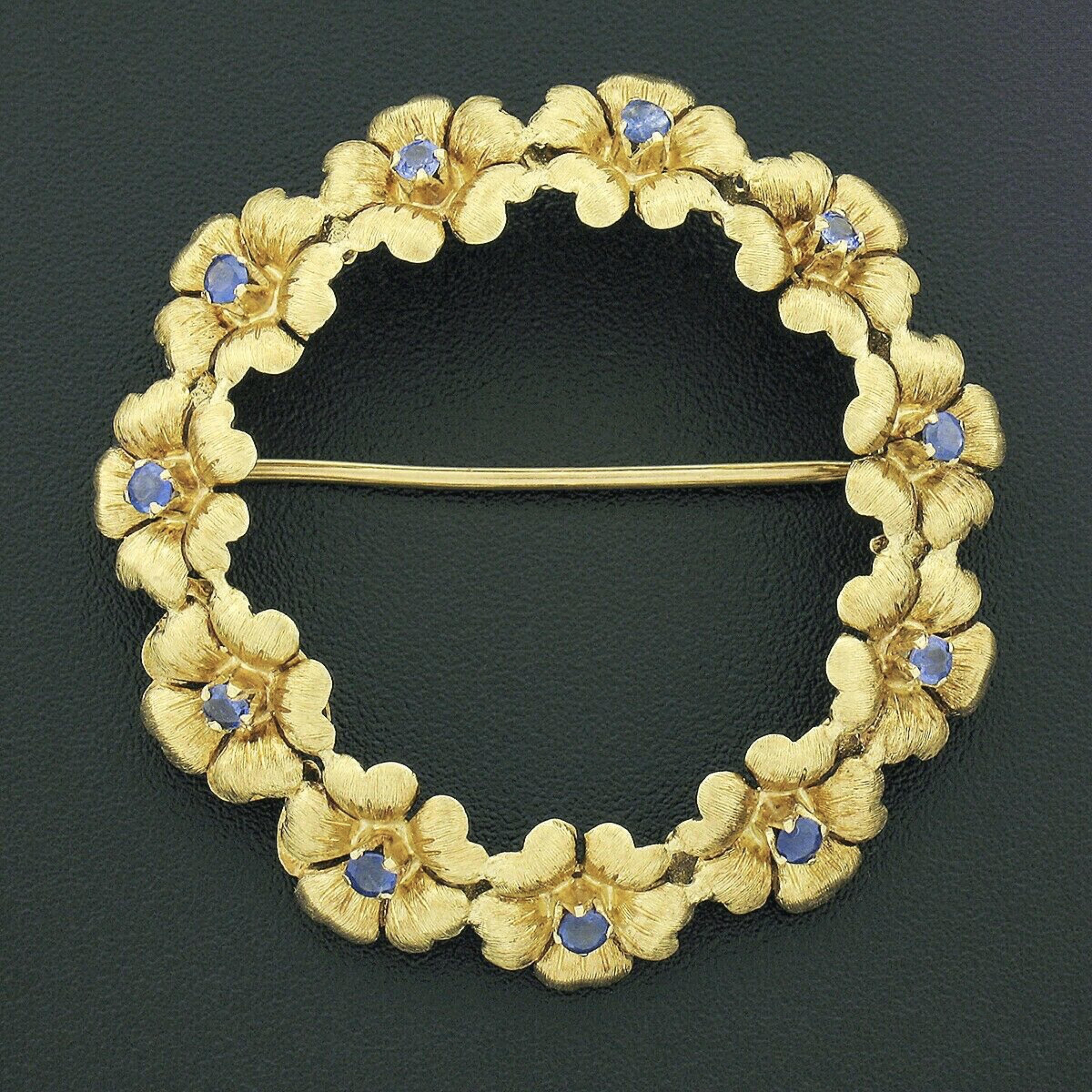 This gorgeous vintage designer brooch was crafted in Italy from solid 18k yellow gold by Tiffany & Co. The wreath style brooch is constructed from textured and engraved flowers with each featuring a fine sapphire neatly set at their center. The 11