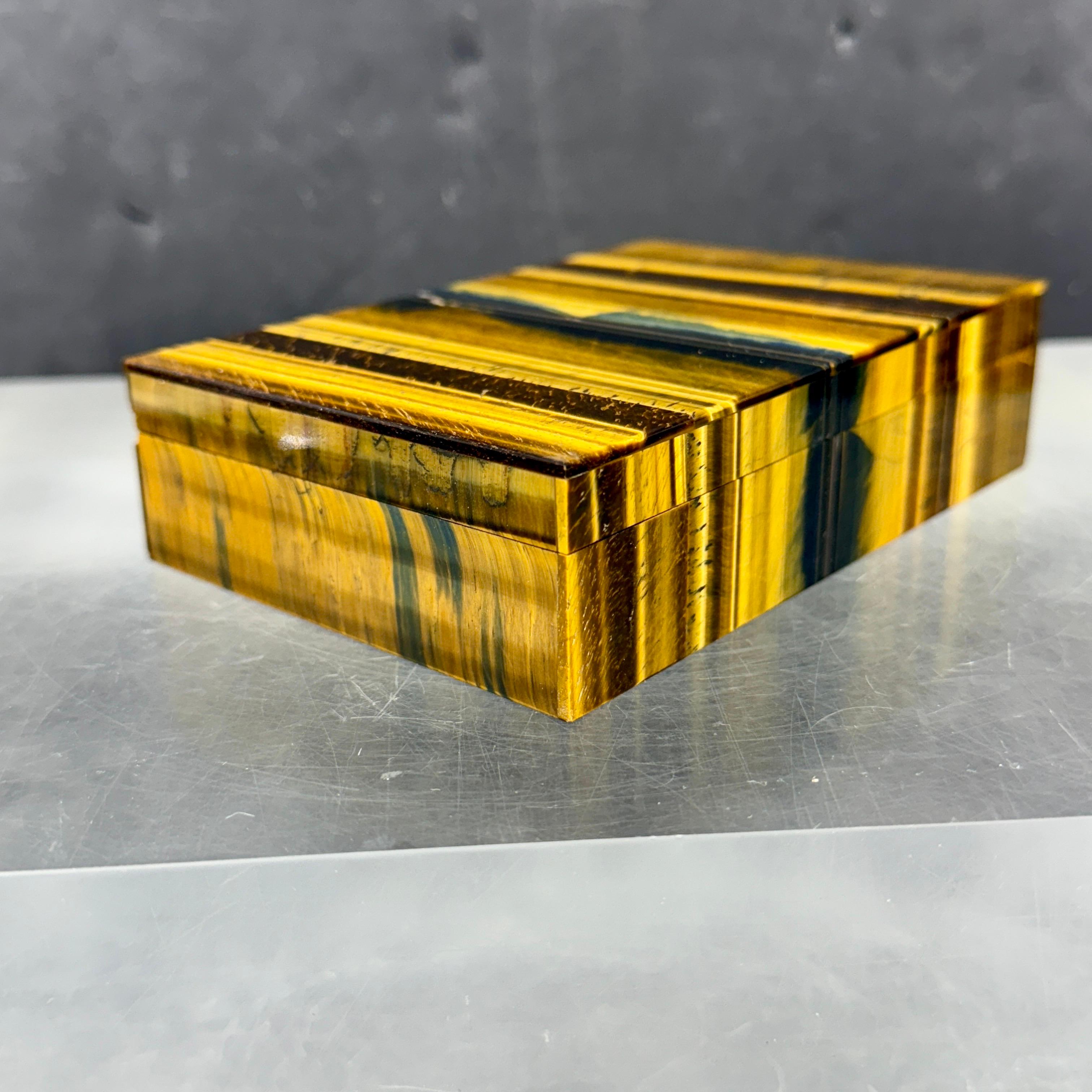 Boîte classique rectangulaire en œil de tigre avec intérieur en pierre noire. Cette pièce se caractérise par sa forme et sa fonction. Cette boîte décorative peut aussi bien contenir vos bibelots préférés que servir de présentoir sur une table basse,