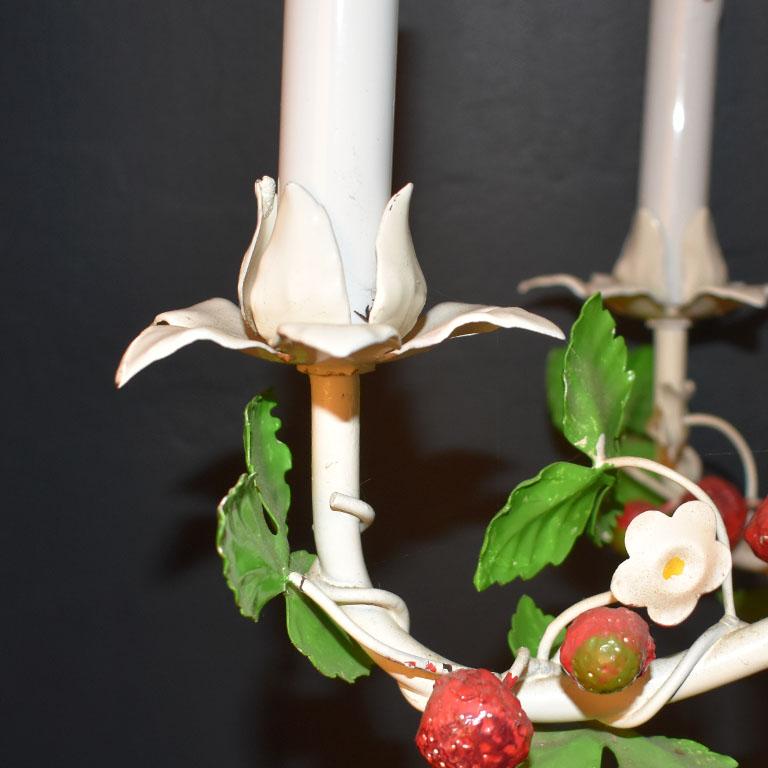 A beautiful strawberry motif tole chandelier. This whimsical piece of lighting features 6 arms with candlestick bulbs. A cream vine of hand-painted green leaves wraps around from the top of the piece throughout the body. Small bright red