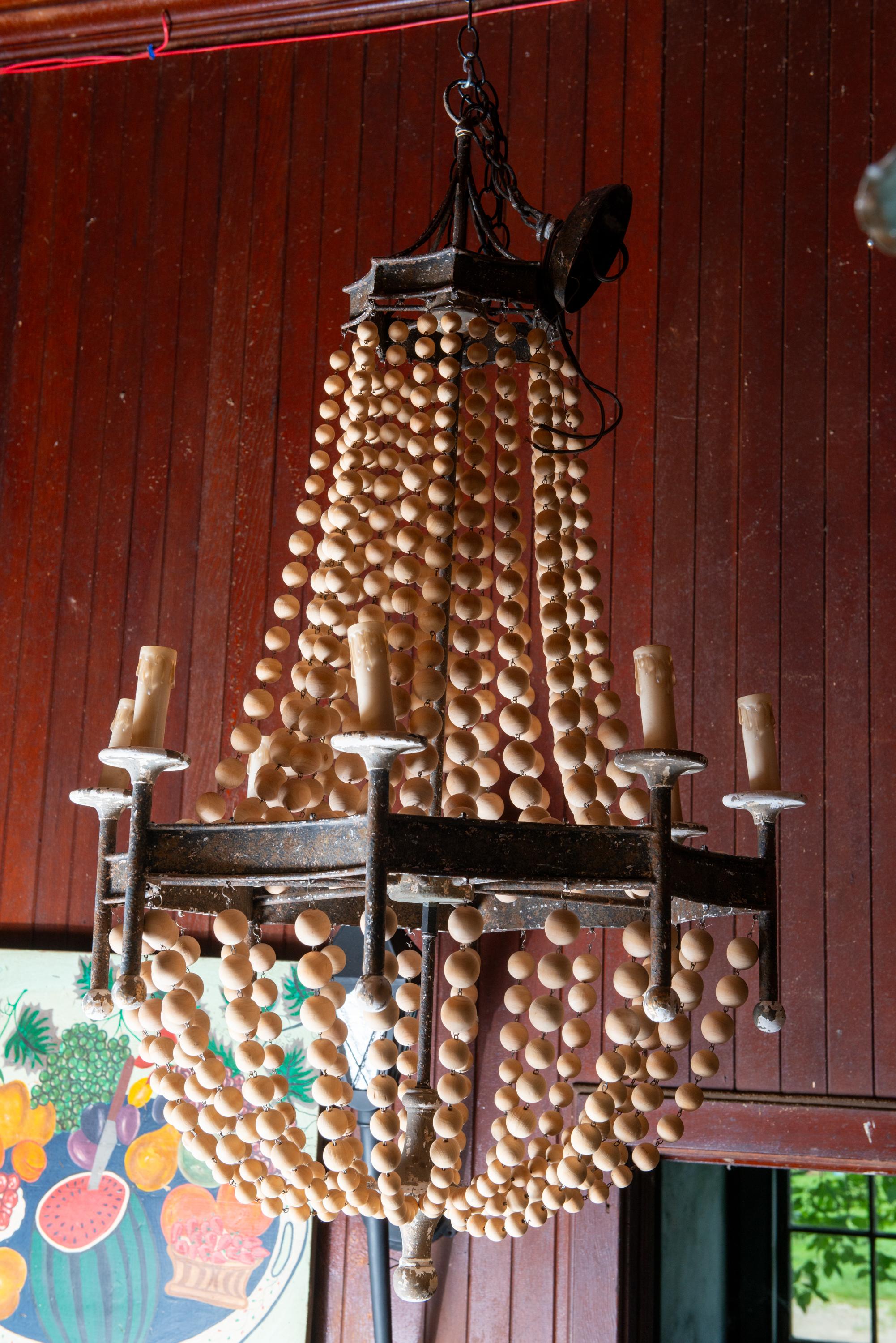 1950s Italian tole and wood beaded chandelier in the Empire style
most likely imported by Chapman Manufacturing Company.  The chandelier consists of an octagonal metal (tole) frame with strands of graduated wood beads and trumpet-shaped mounts under