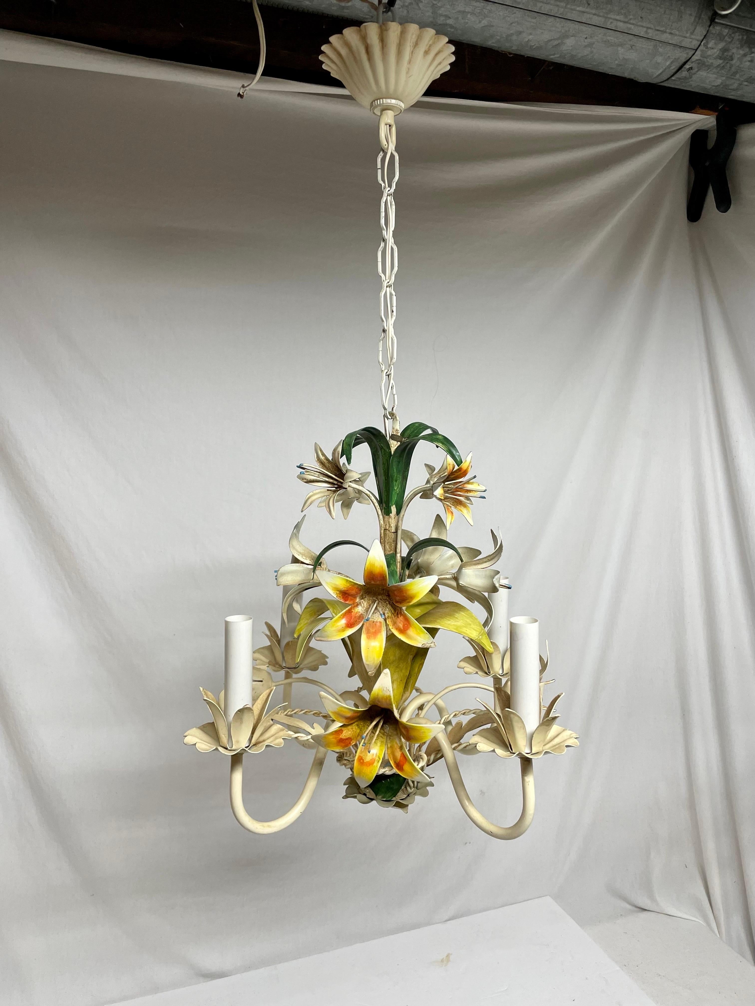 Italian floral tole four arm chandelier. Lots of  Lily flowers in cream and yellow-reds with green leaves.  Some chipping paint that adds to the character. In good working condition. Measures: 16