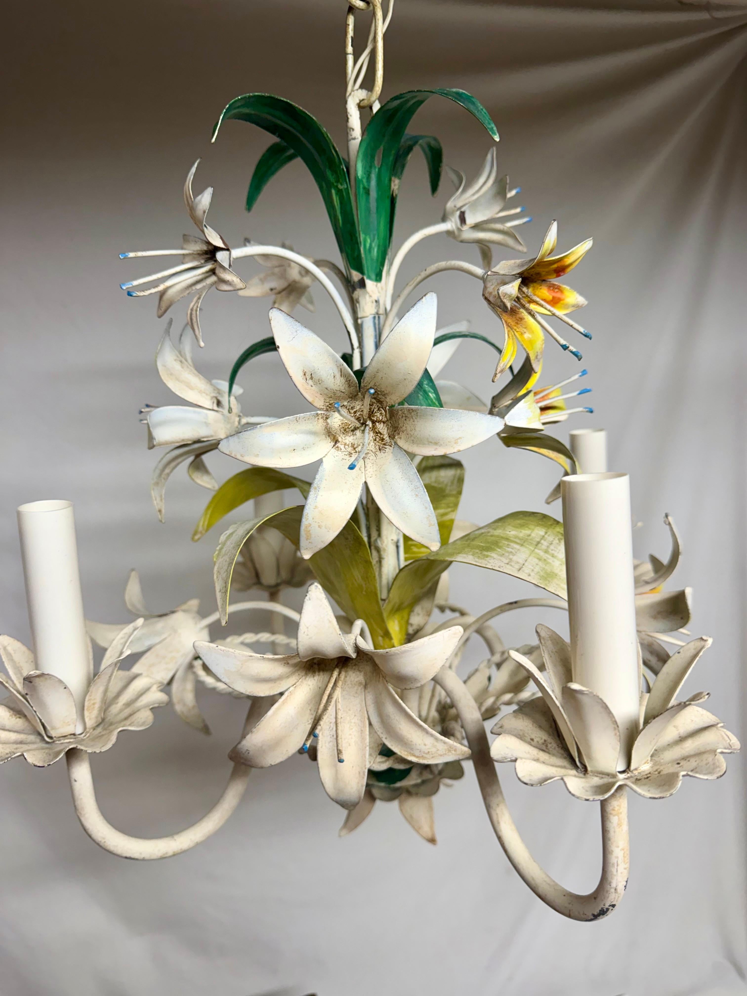  Lampadario a quattro bracci con tole floreali italiane.  Fiori di The Lilly nei colori giallo, arancione e crema. Foglie in verde e giallo. Alcune scheggiature della vernice ne esaltano il carattere. In buone condizioni di funzionamento. Misure: