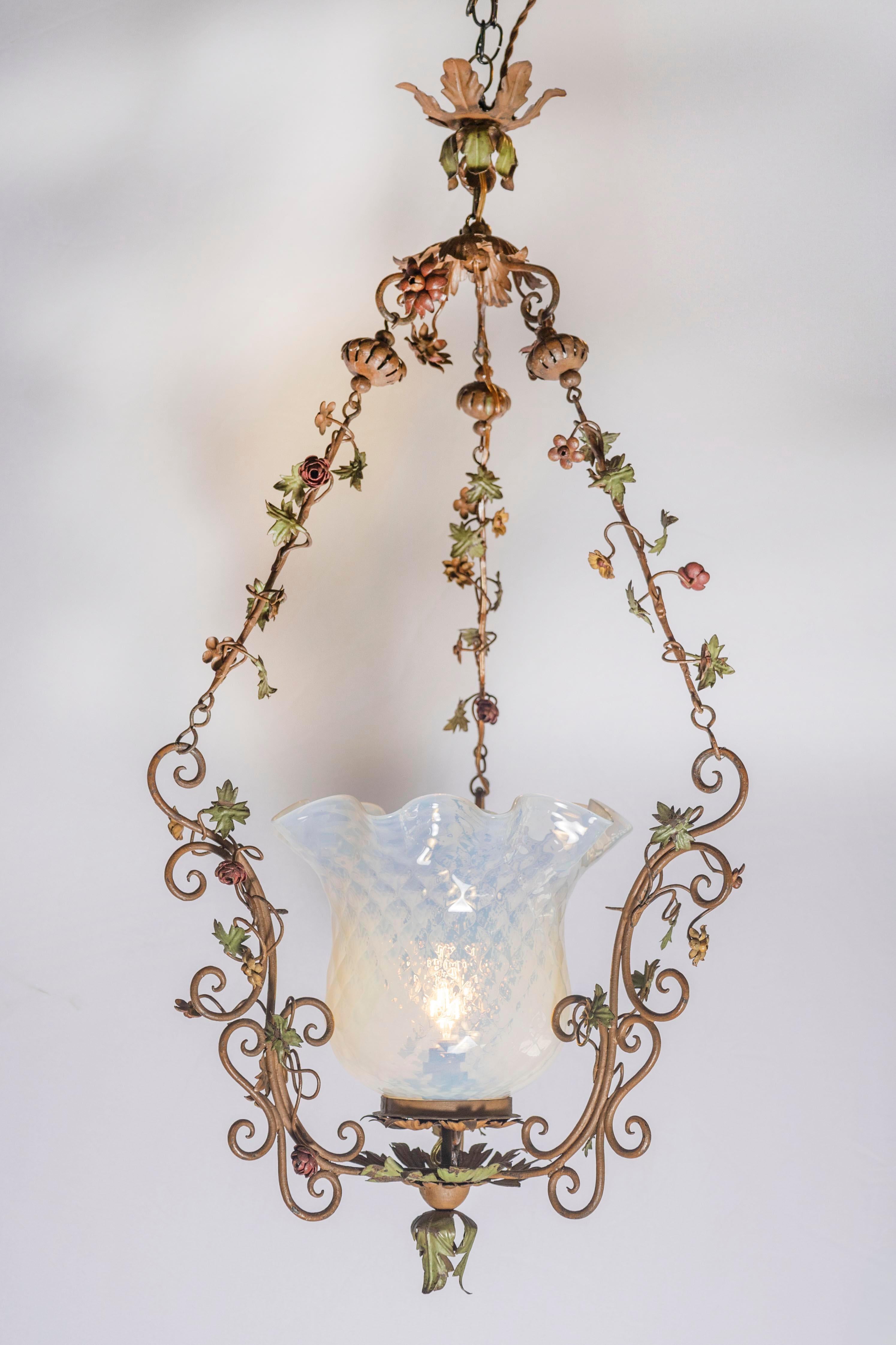 Diese bezaubernde italienische Laterne aus der Mitte des 20. Jahrhunderts ist ein wahres Fest der Handwerkskunst und der botanischen Eleganz und erinnert an die romantische Laune eines blühenden Gartens. Der durchbrochene Eisenrahmen hängt an zarten