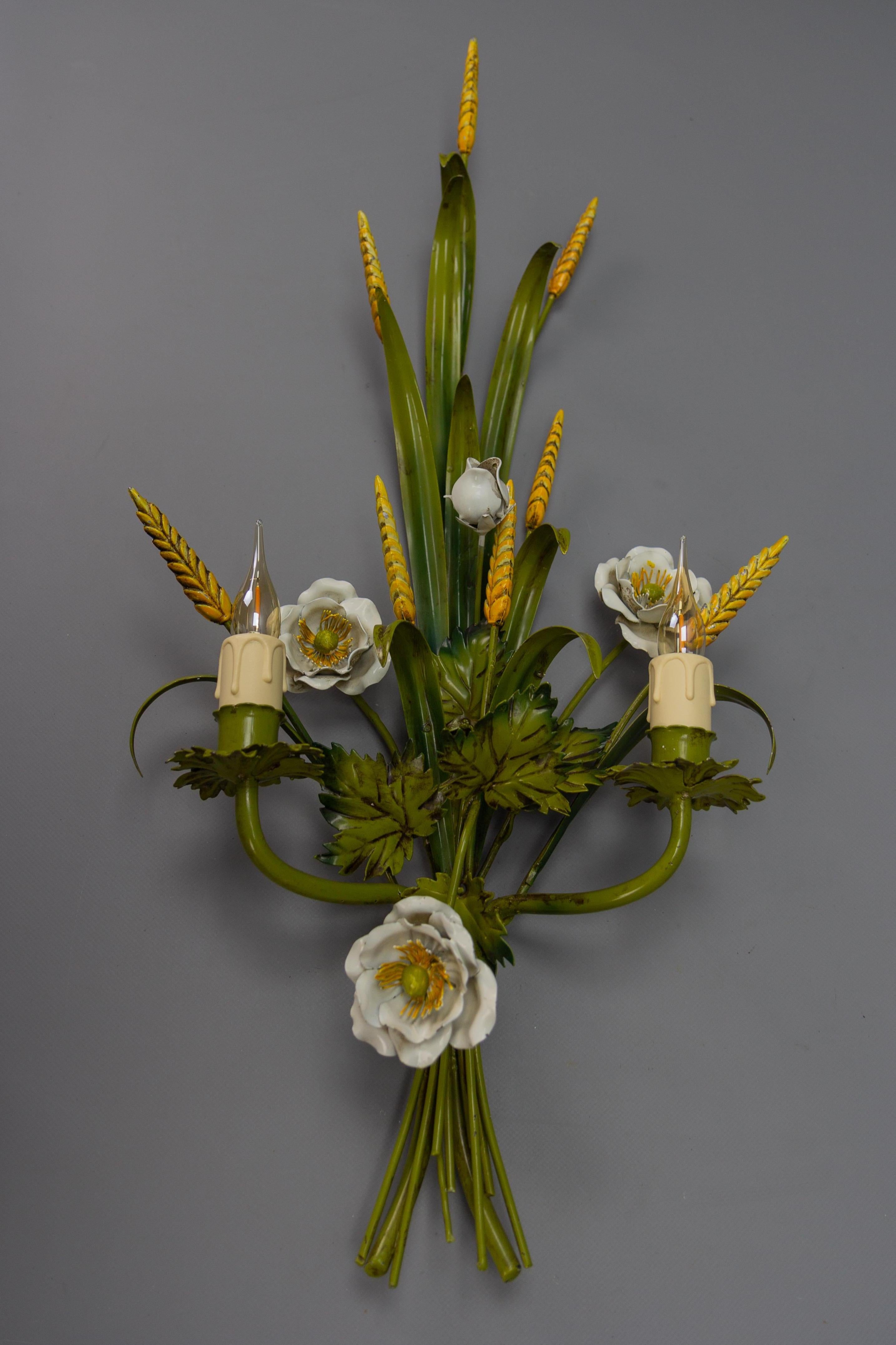 Italian toleware white poppy and wheat green floral bouquet two-light sconce from circa the 1960s.
A decorative Italian toleware twin-light wall lamp painted in white, green, and yellow colors, featuring a bouquet of white poppies, wheats, and
