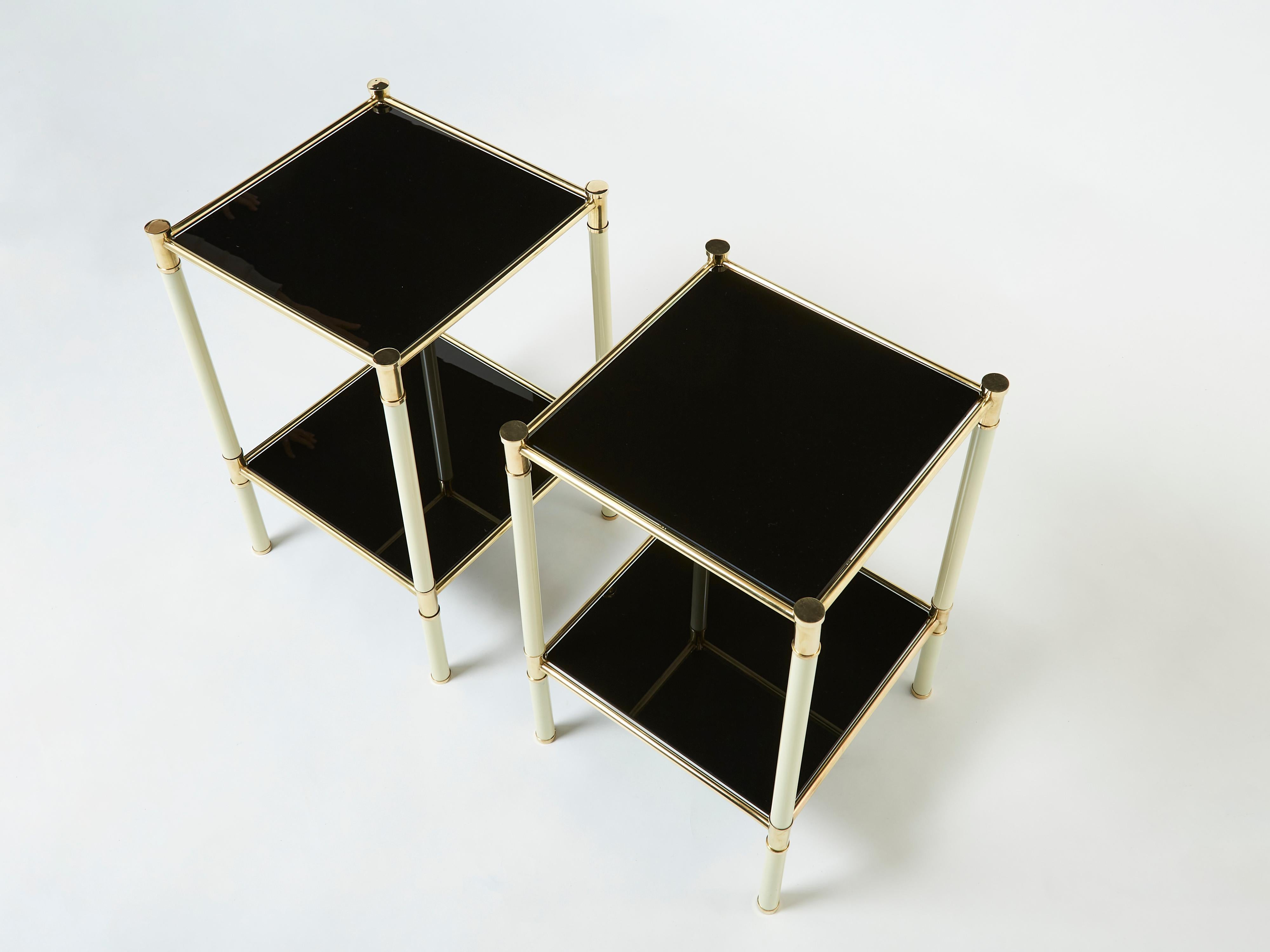 This pair of two-tier end tables, or nightstands, were designed by Italian mid-century modern designer Tommaso Barbi. They were created with off white metal feet with brass accents, and beautiful black opaline glass tops circa 1970. The two-tier