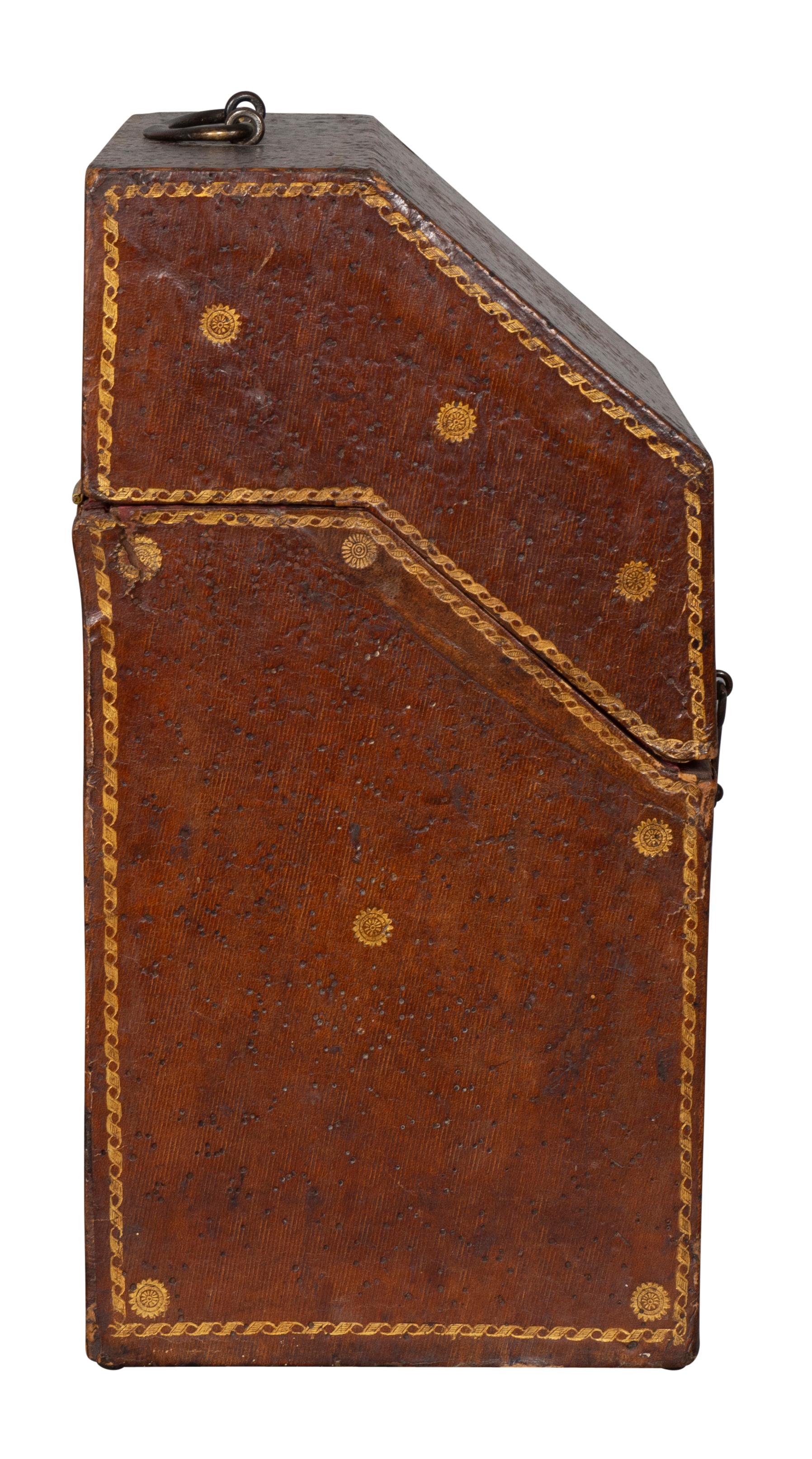 Slant hinged lid opening to a fitted compartment and conforming case with overall tooled decoration. Iron handle and latches.