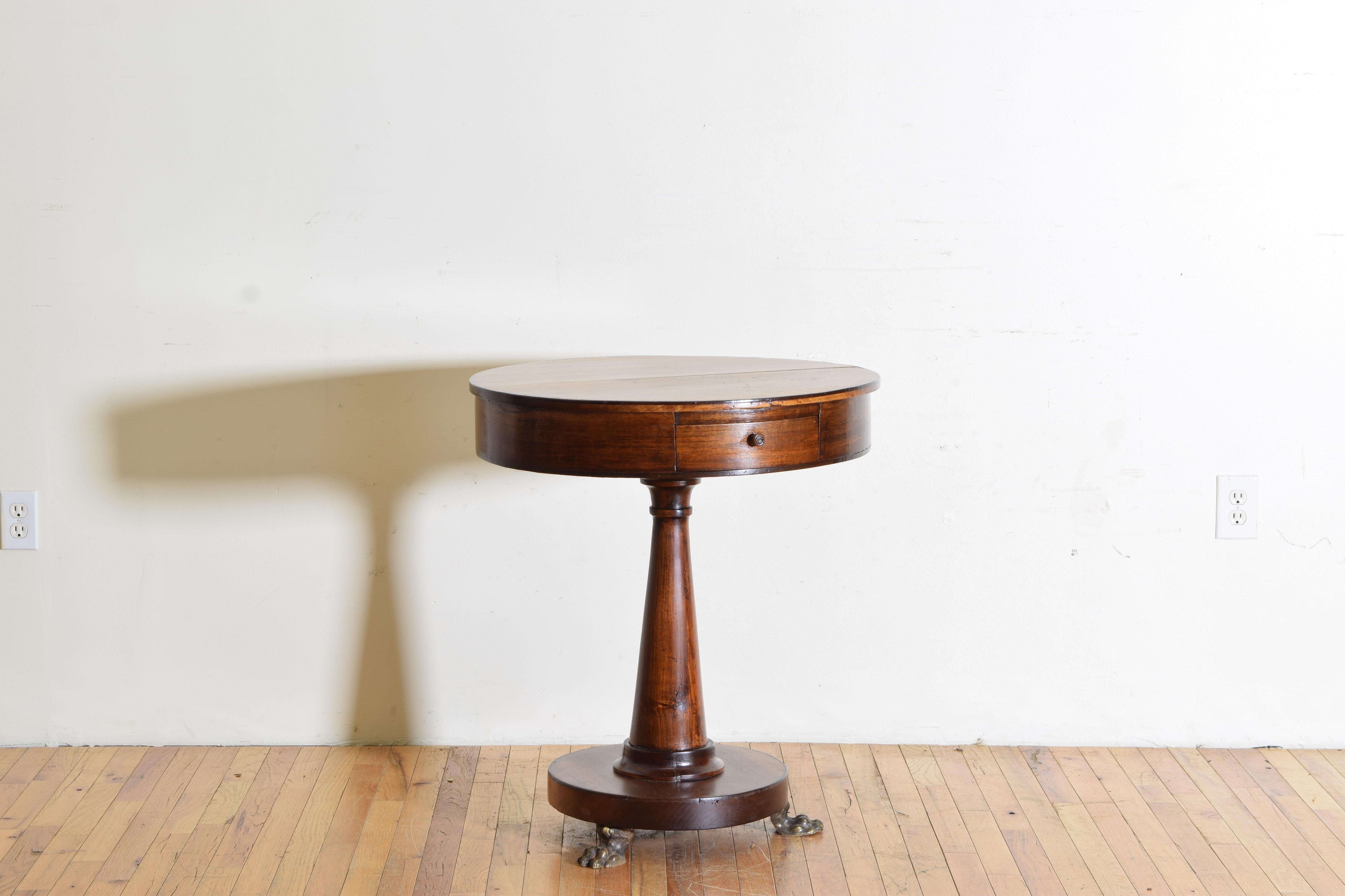 having a circular top with a small outer band of ebonized wood and housing two drawers, the tapering solid walnut standard atop a circular base with ebonized outer band, the base resting on lion's paw gilt brass feet