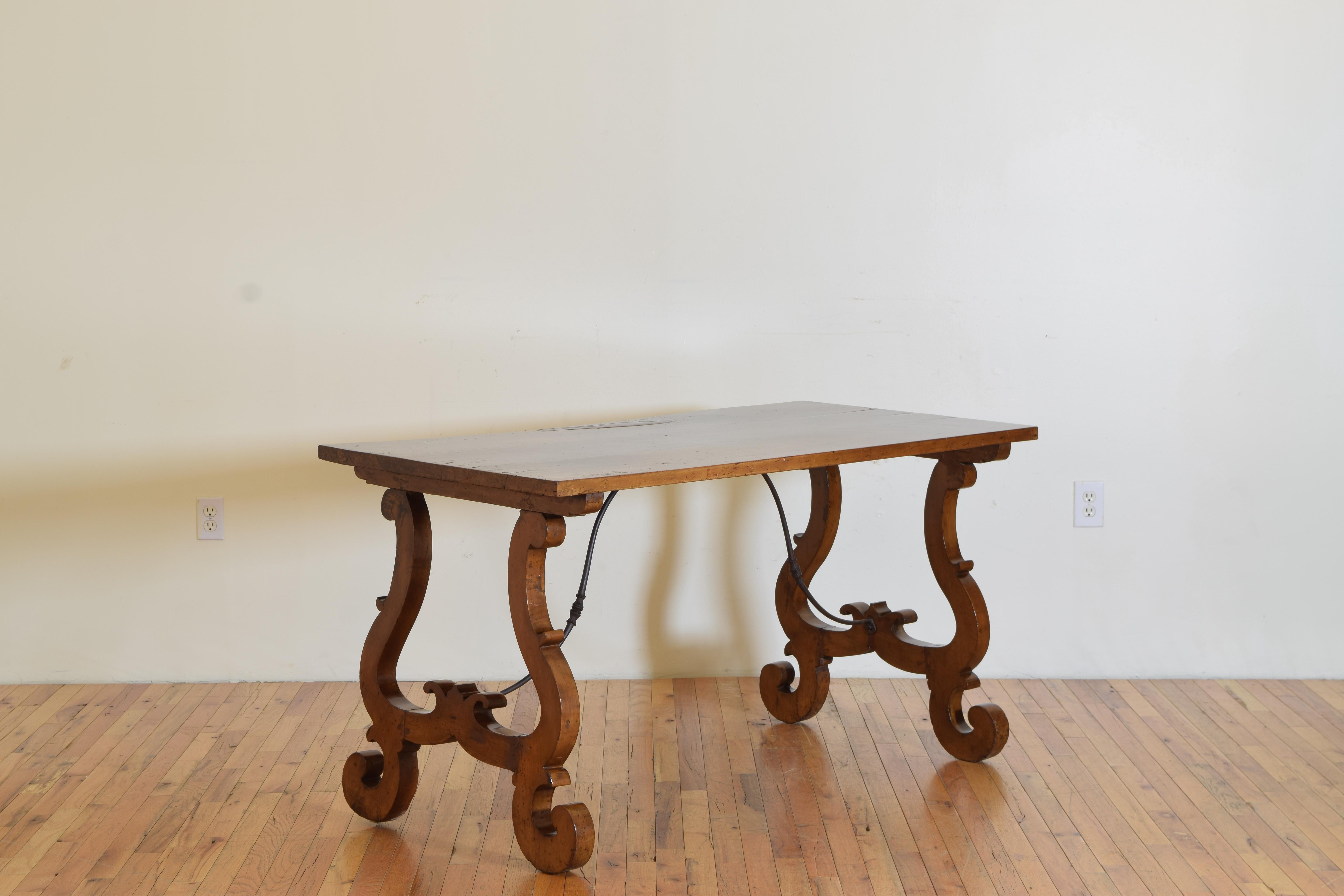 The rectangular top with a distinguishing raised burl supported by elegantly shaped legs and braced by iron stretchers.