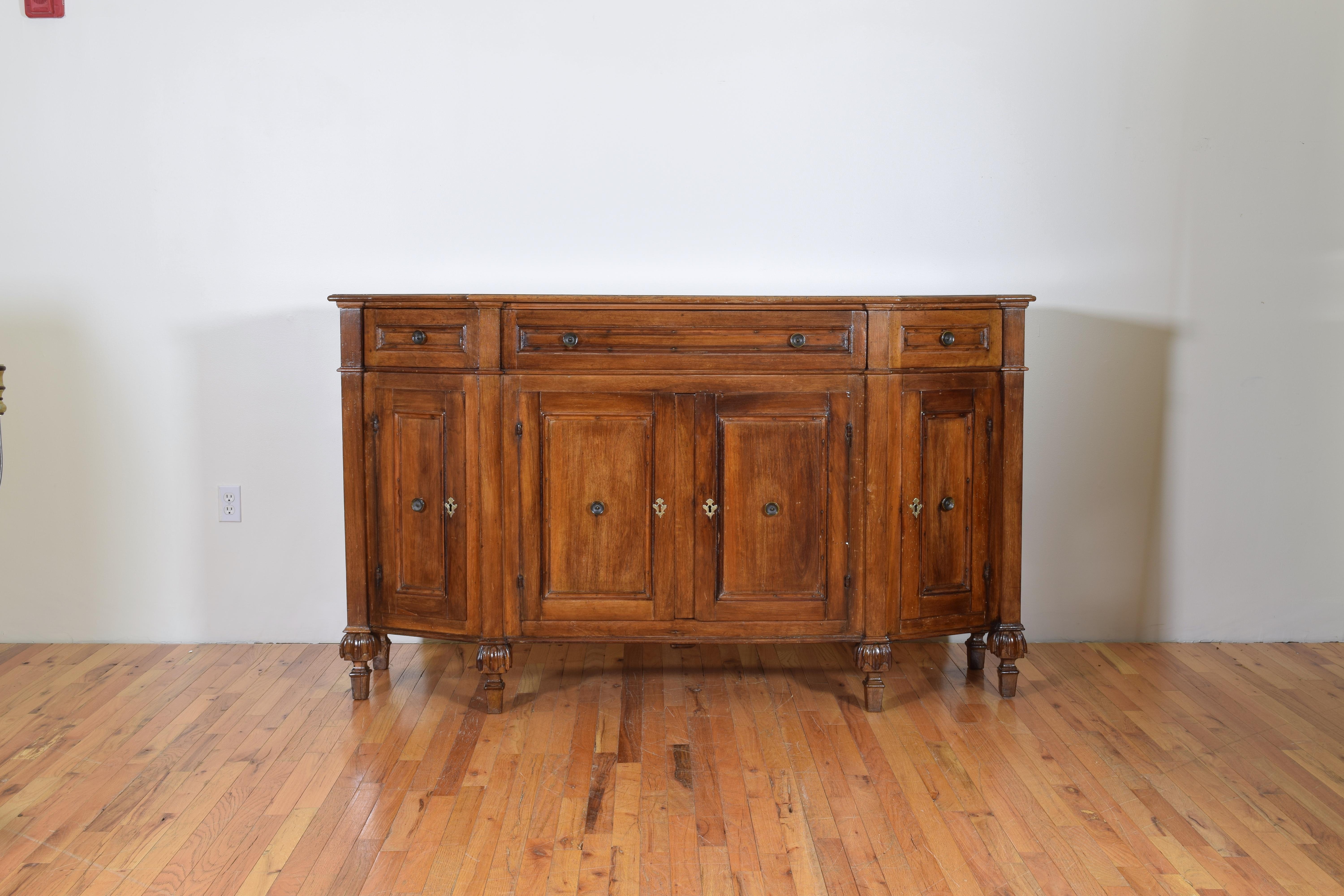 Of scantonata form and having paneled drawer and door fronts, 3 drawers over 4 doors, the case raised on interestingly carved feet, retaining period locks and keys.