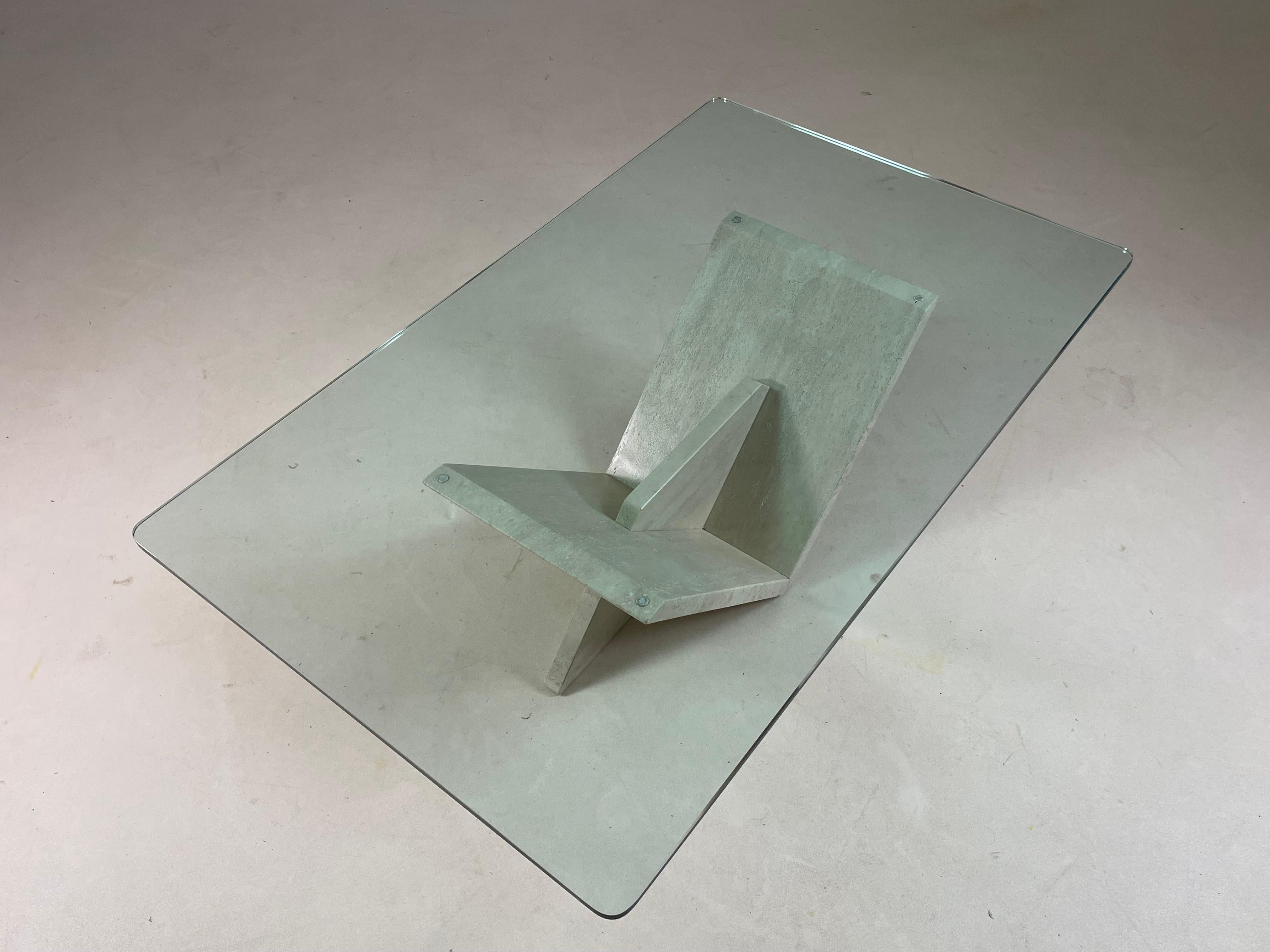 Bringen Sie mit diesem einzigartig gestalteten Couchtisch einen Hauch von zeitgenössischer Raffinesse in Ihr Interieur. Sein Sockel aus natürlichem Travertin in V-Form verkörpert die perfekte Mischung aus roher Mineralität und modernen