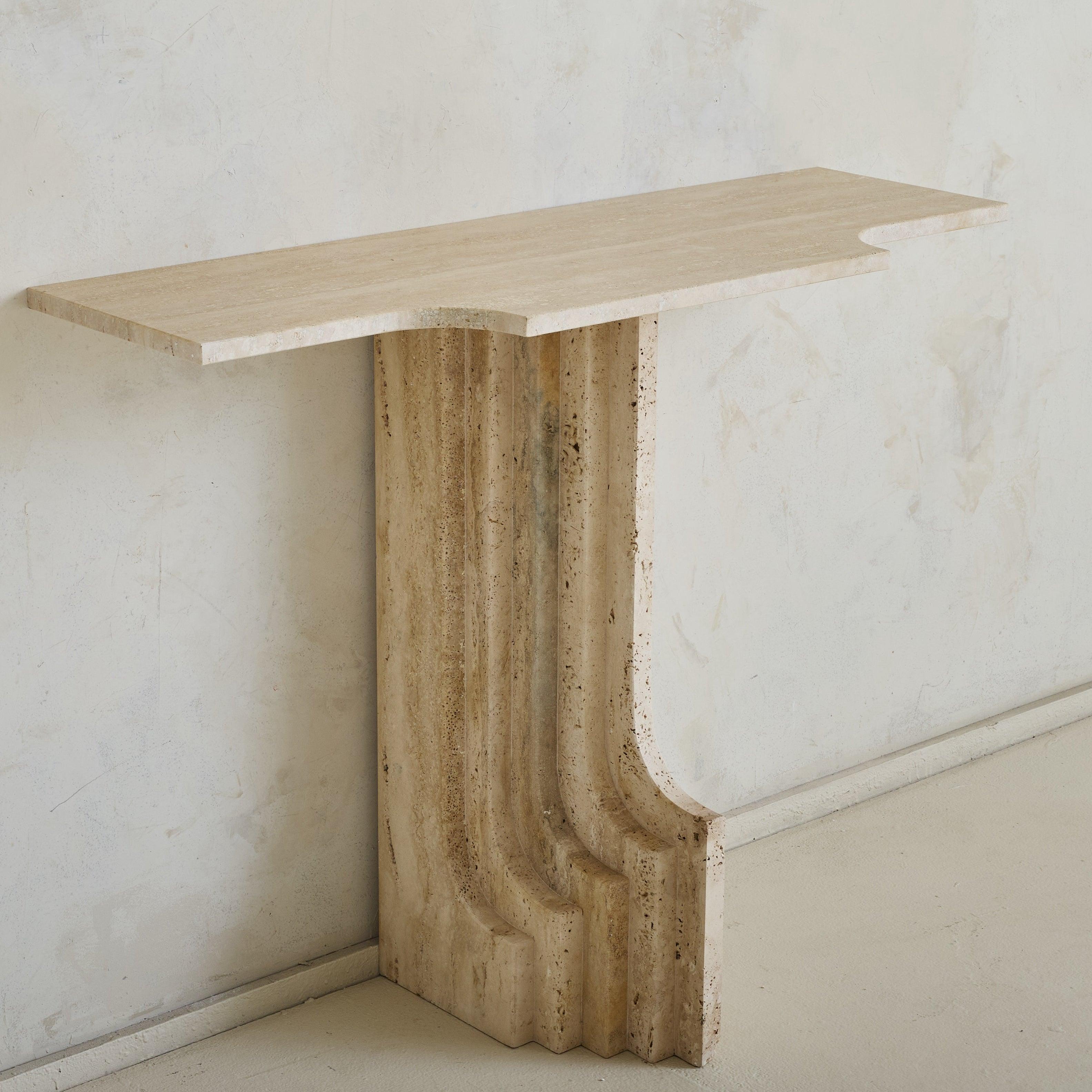 Vendus et tarifés individuellement.

Cette console italienne en travertin des années 1970 incarne l'éthique sculpturale de Carlo Scarpa. La base cannelée monolithique, avec ses détails rythmiques en escalier, rappelle l'approche caractéristique de