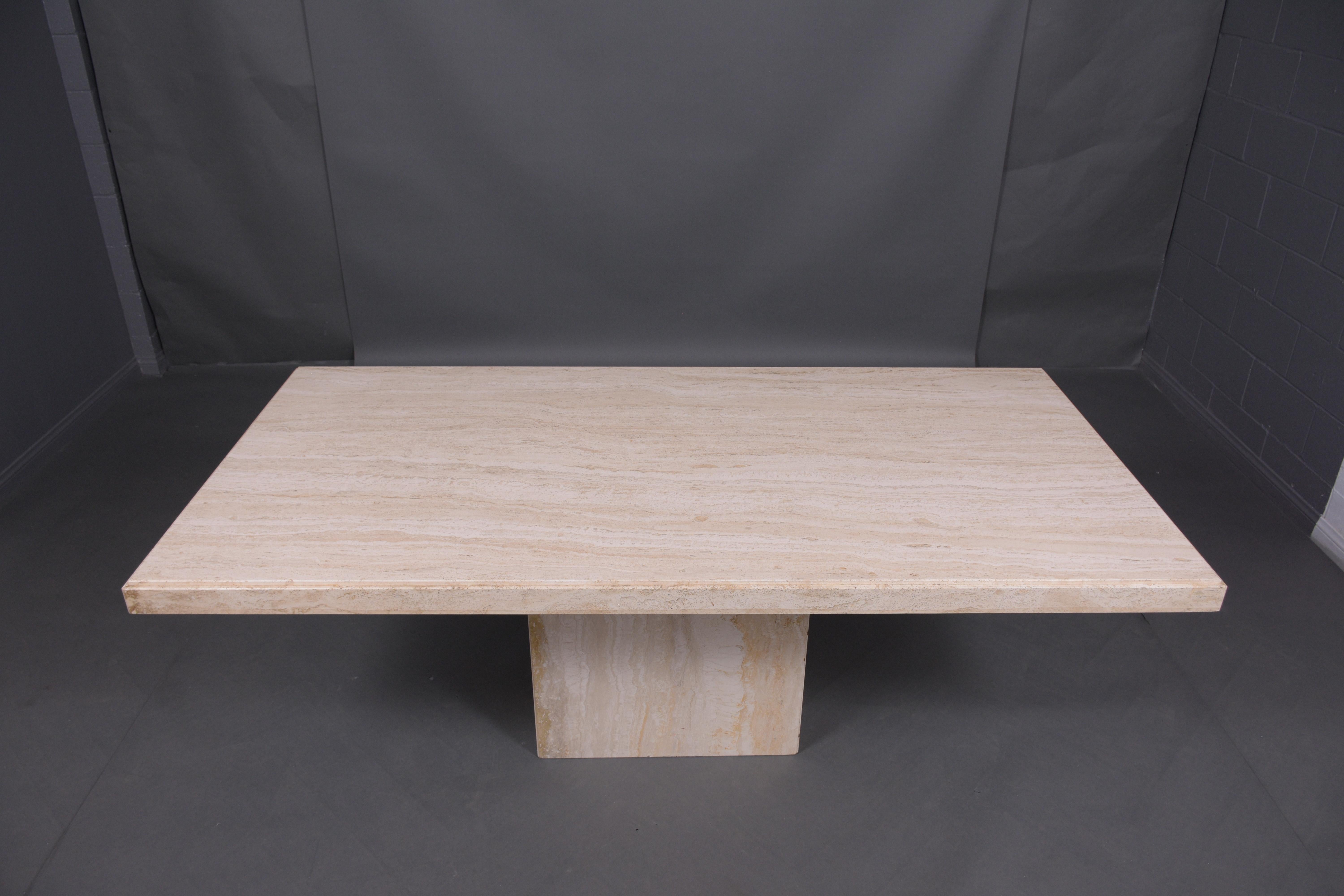 An extraordinary 1970s dining room table hand-crafted out of travertine marble stone. This table has an eye-catching feature large rectangular shape top with an uprising around the edges and seats on a floating base, This minimalist dining marble