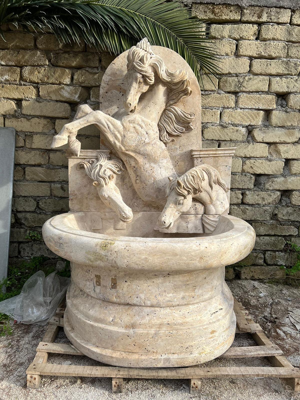 Fontana decorativa scolpita in marmo travertino dai toni caldi, con motivi a testa di cavallo finemente scolpiti. Realizzato in Italia negli anni '80, questo pezzo presenta un'armoniosa miscela di ispirazione classica e artigianato. Le teste di