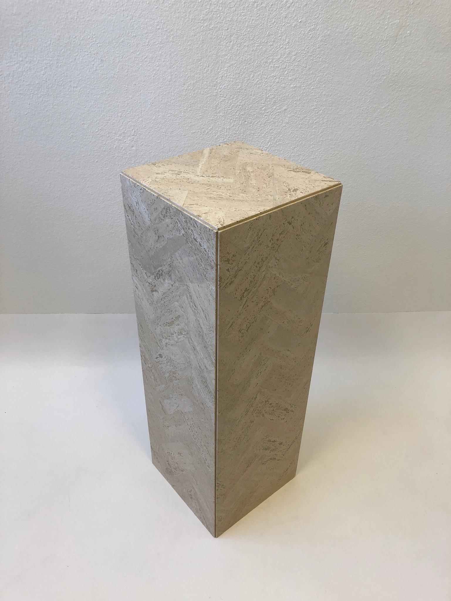 A glamorous Italian travertine pedestal from the 1970s. The pedestal is constructed of tessellated travertine in a herringbone pattern. 
Measurements: 36” high, 12” wide, 12” deep.
