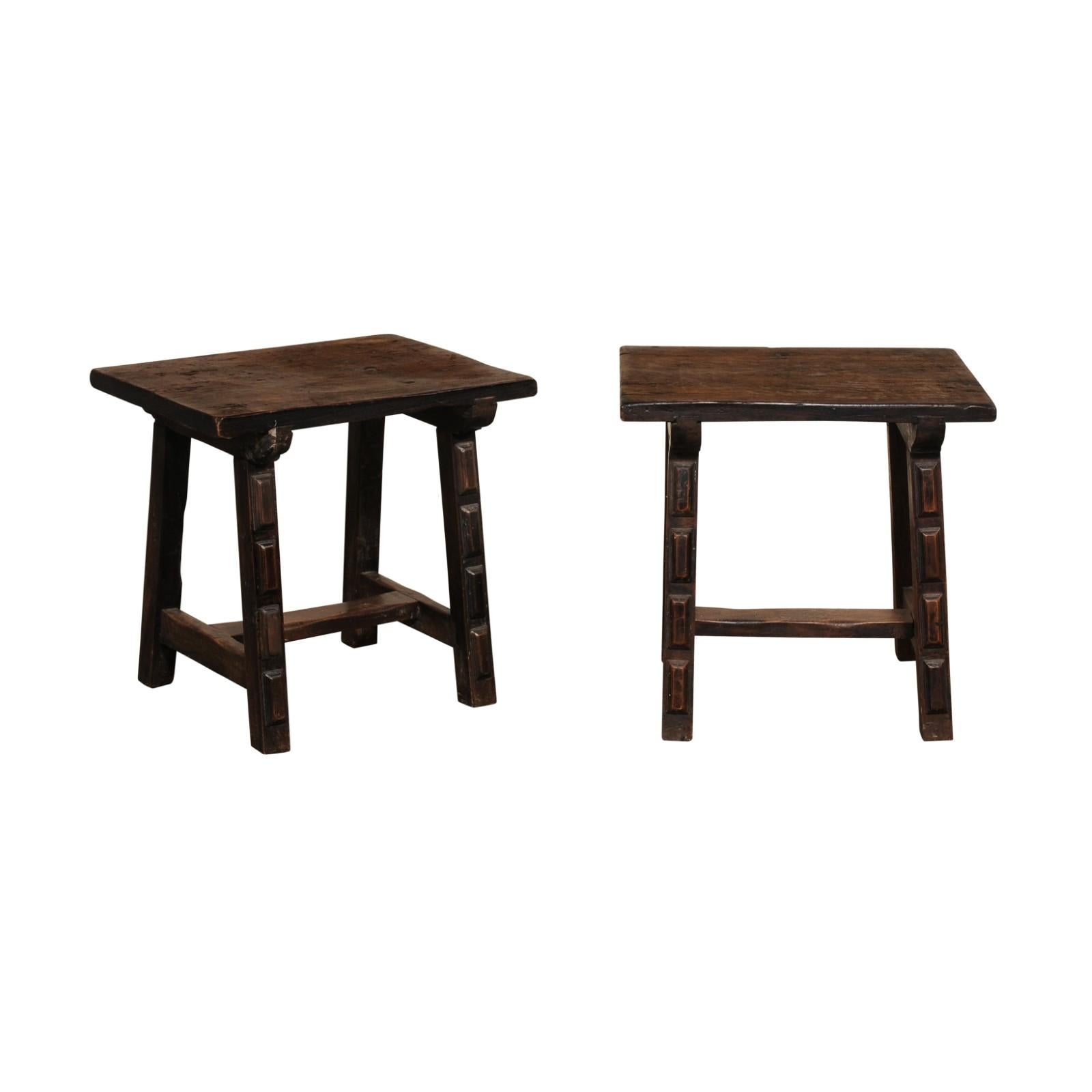 A rustic Italian pair of carved wood side tables, with trestle legs, from the 19th century. This pair of small antique tables from Italy each feature rectangular-shaped tops that are raised upon a pair of saw-horse style, trestle legs, each carved