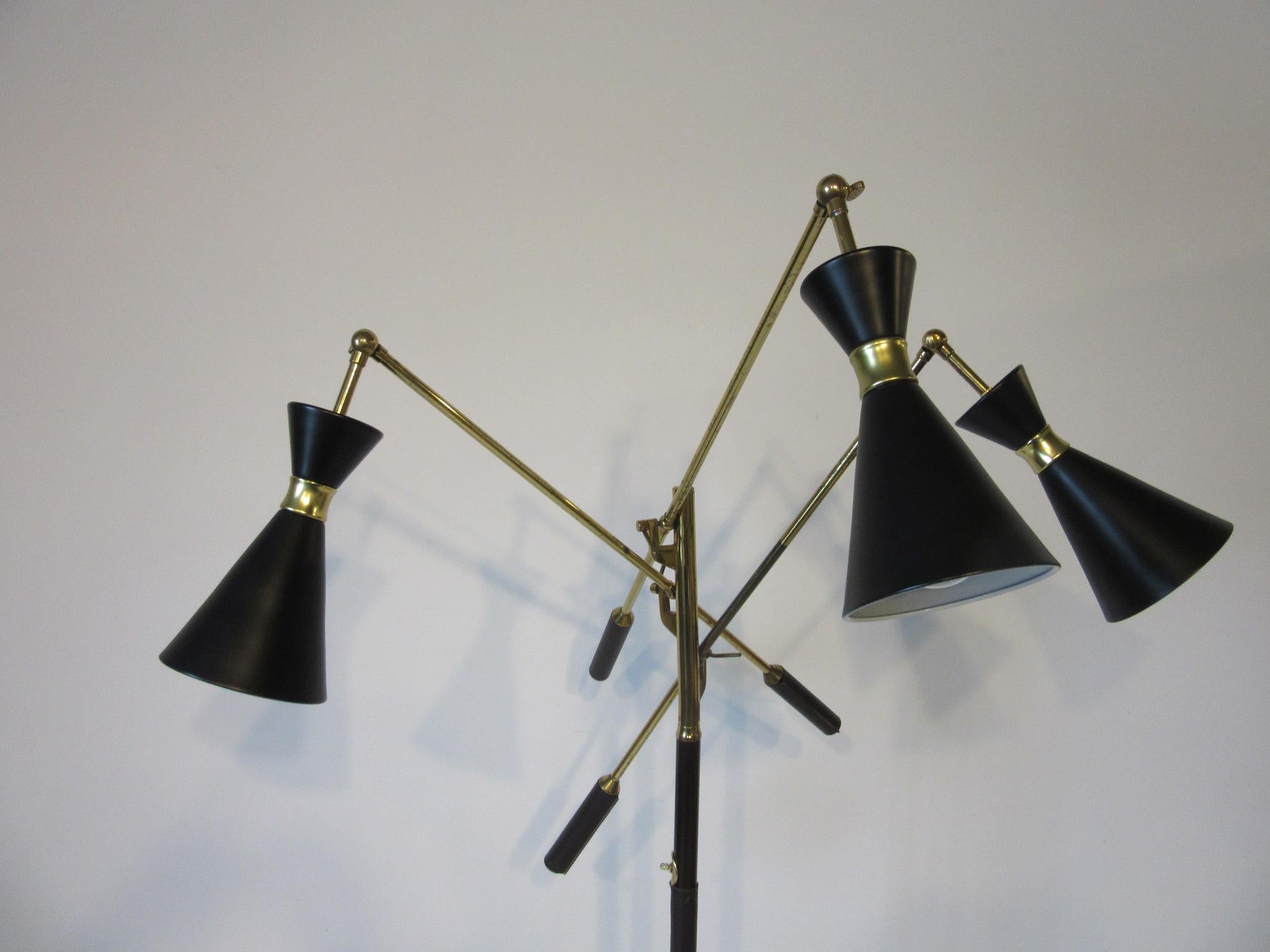 An adjustable arm floor lamp with brass and black metal shades, brass arms and accents and a gray black Carrara marble base. Brass on and off switch on the pole which is a very dark brown complementing the dark brown leather handles. The lamp has a
