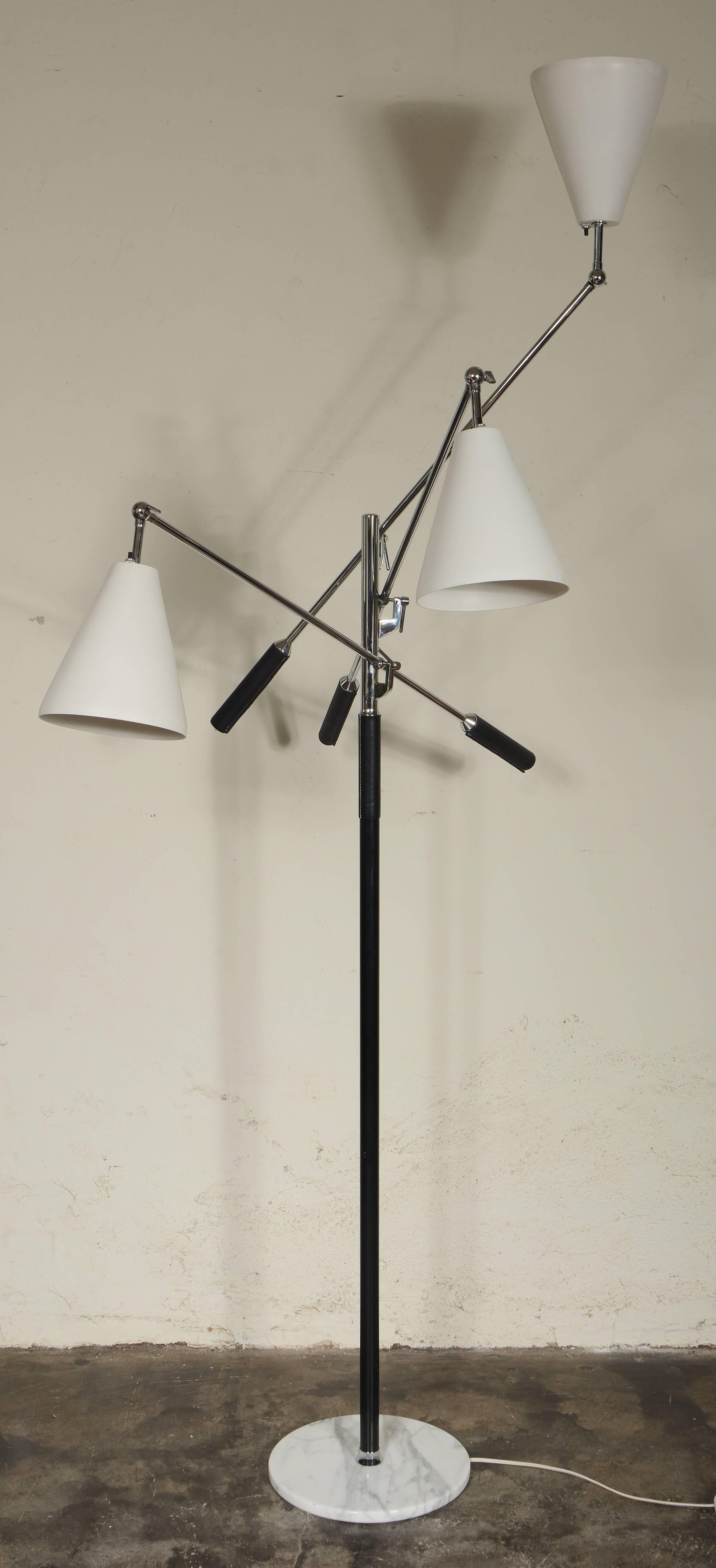 Adjustable three-arm floor lamp after a model by Arredoluce. This has three white enameled shades and a marble base. This is marked Made Italy on the top of the column. The lamp has a floor switch as well as individual switches on the shades. There