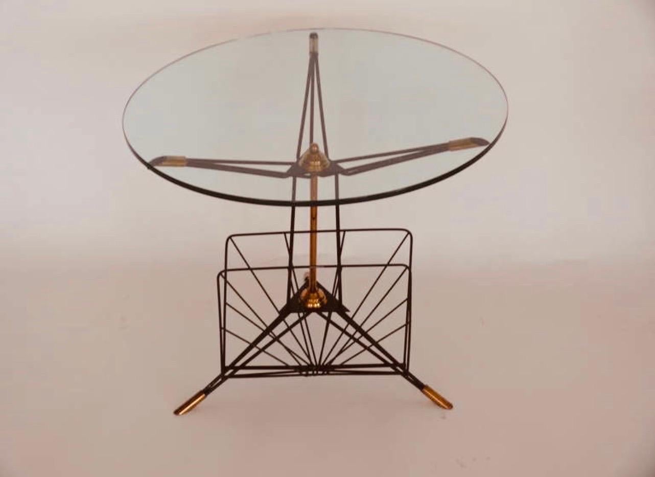 A charming Italian tripod side table with a built in magazine rack made from metal and brass with a glass top.