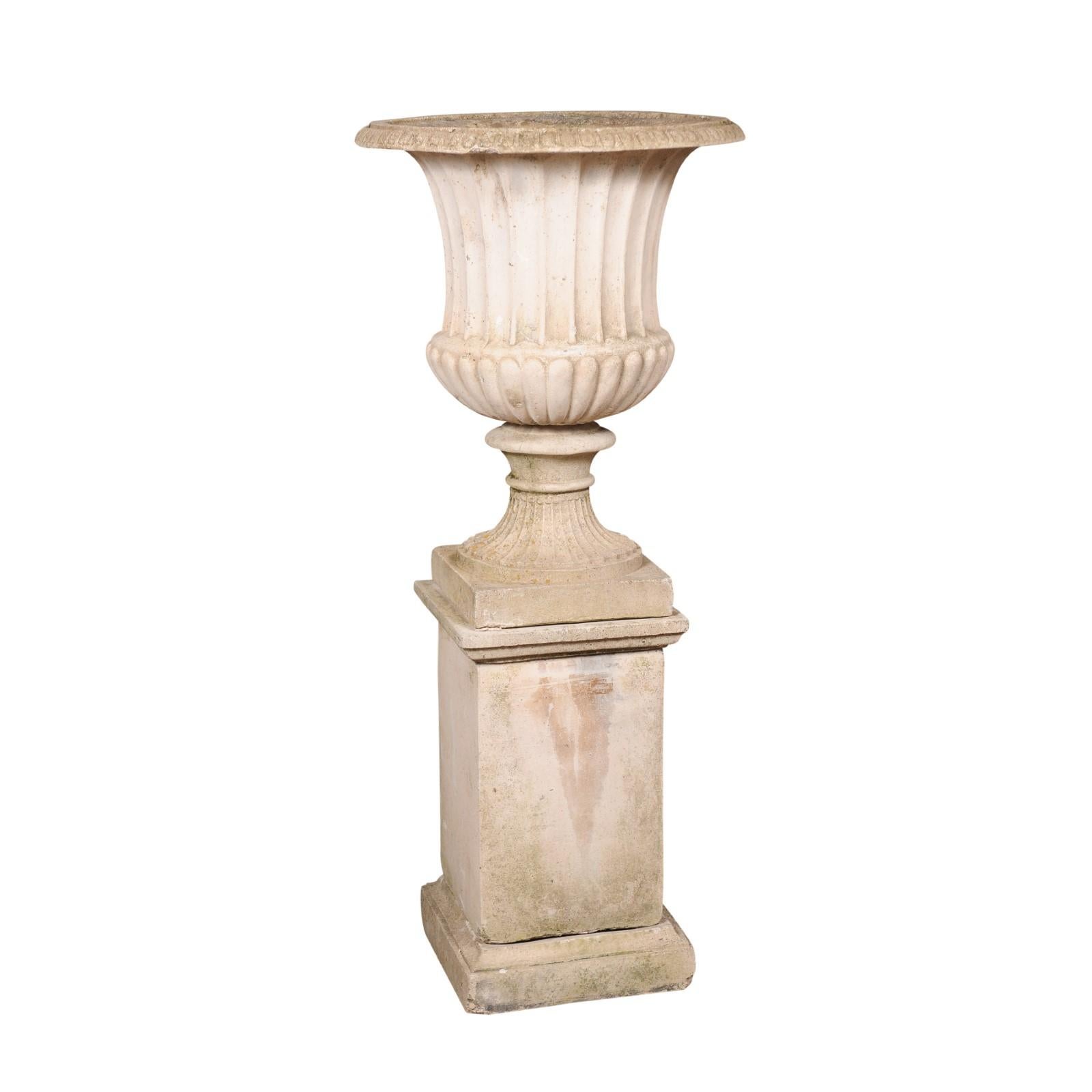 An Italian Turn of the Century Campania urn from the early 20th century, with gadroon motifs, flaring shape and tall pedestal. Made of reconstituted stone in the early years of the 20th century, this Italian Campania urn captures our attention with