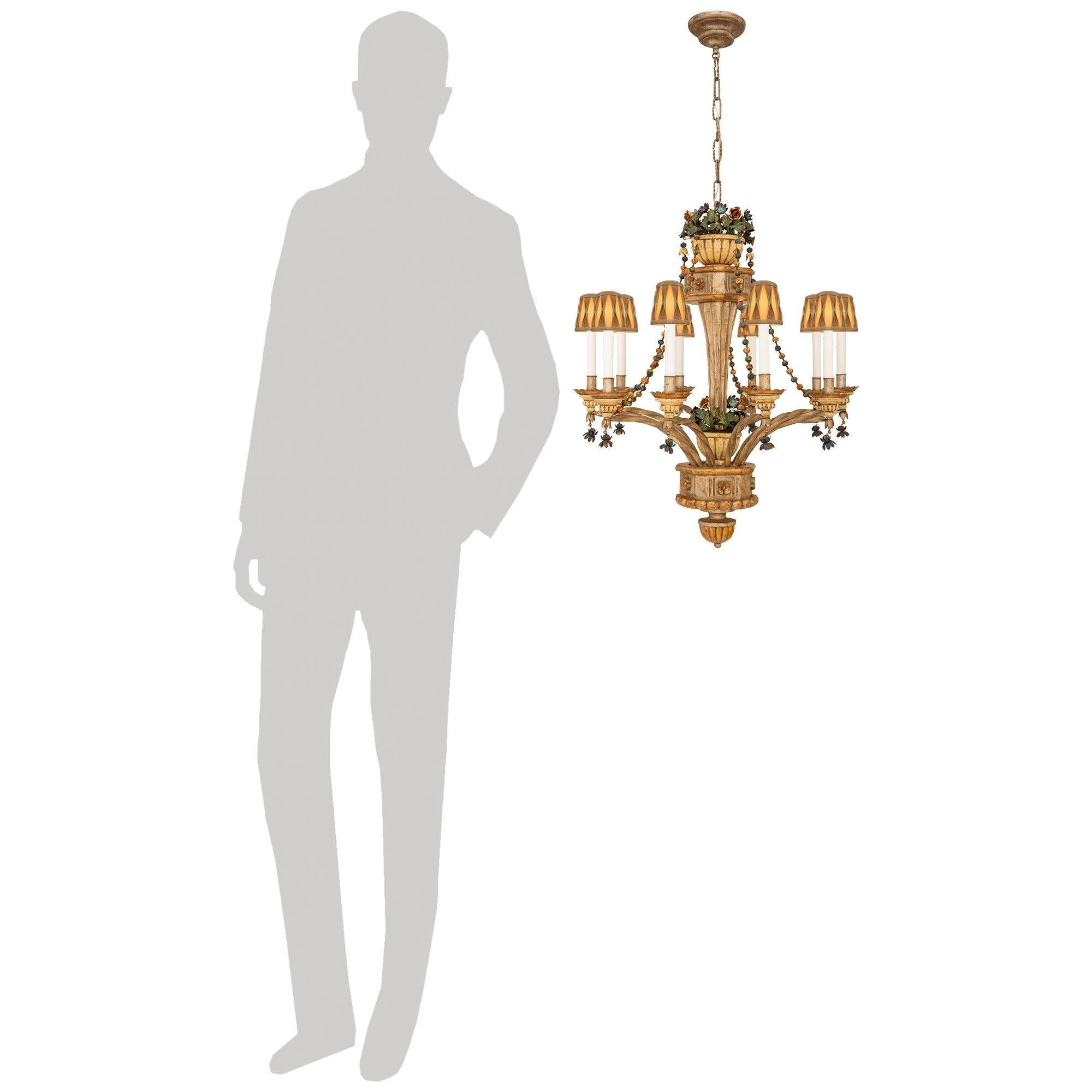 A lovely and most whimsical Italian Turn of the Century Louis XVI st. Pressed Metal, Tole, and Patinated wood chandelier. This most decorative ten light chandelier is centered by a topie shaped bottom finial with a dentil pattern. The finely carved