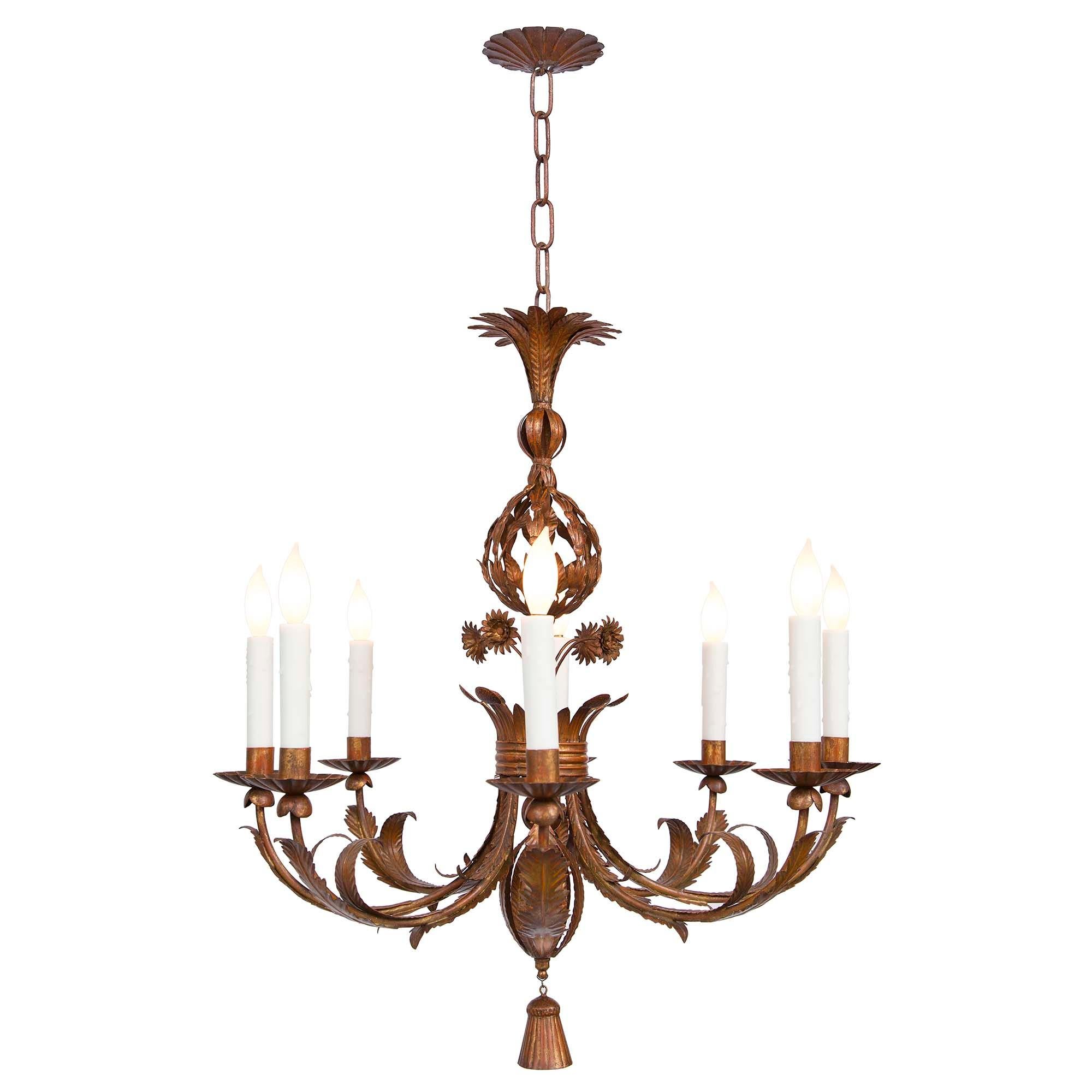A beautiful Italian turn of the century pressed metal eight arm chandelier. The chandelier is centered by a charming tassel pendant below foliate movements which lead out and adorn each arm. At the center is a crown like design with lovely pressed