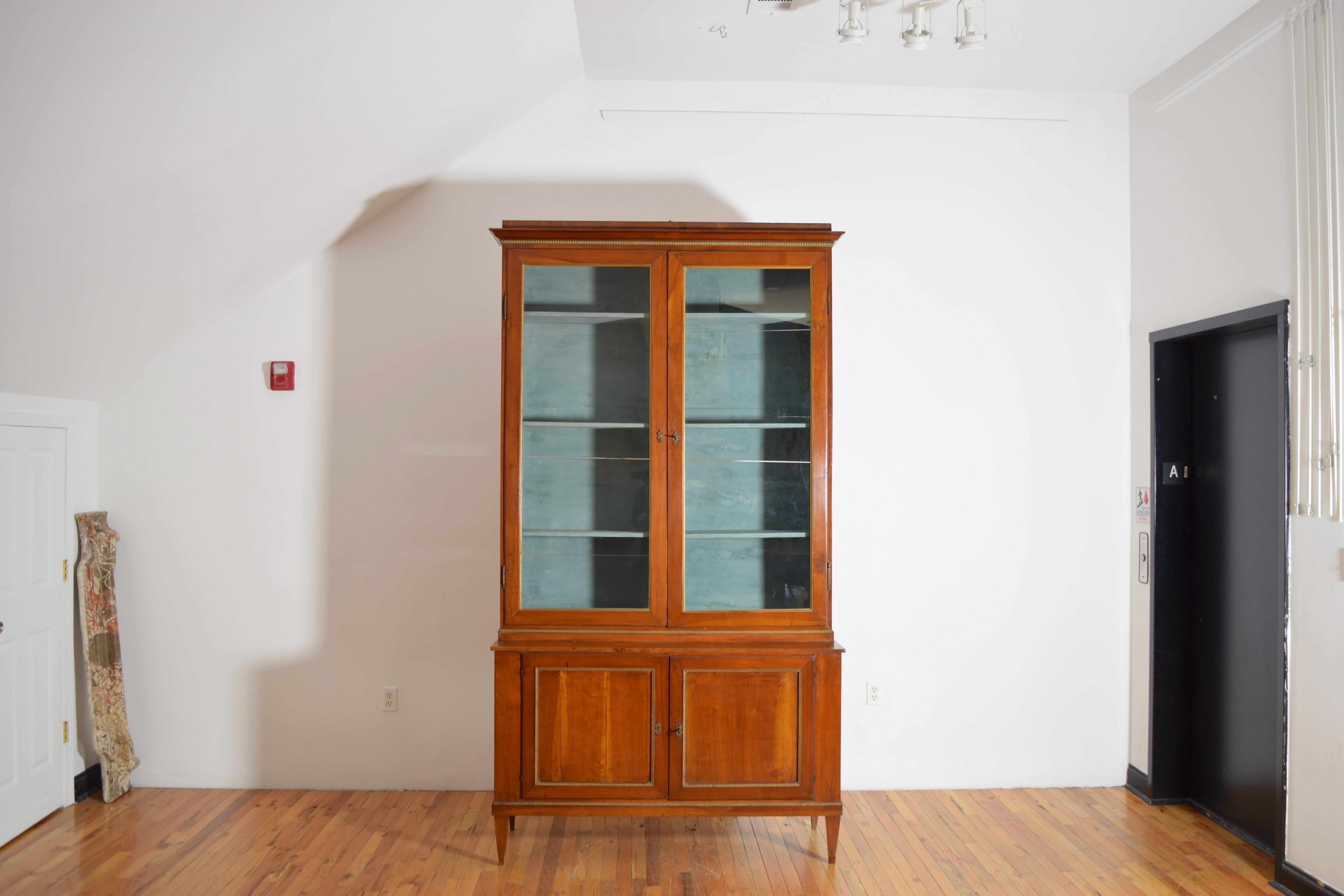 Une élégante paire d'armoires en bois fruitier et verre du début du 19e siècle provenant de la région de Toscane en Italie.  Chacune est constituée de deux pièces, la paire de coffrets présentant des détails sculptés en bois doré le long du haut, du