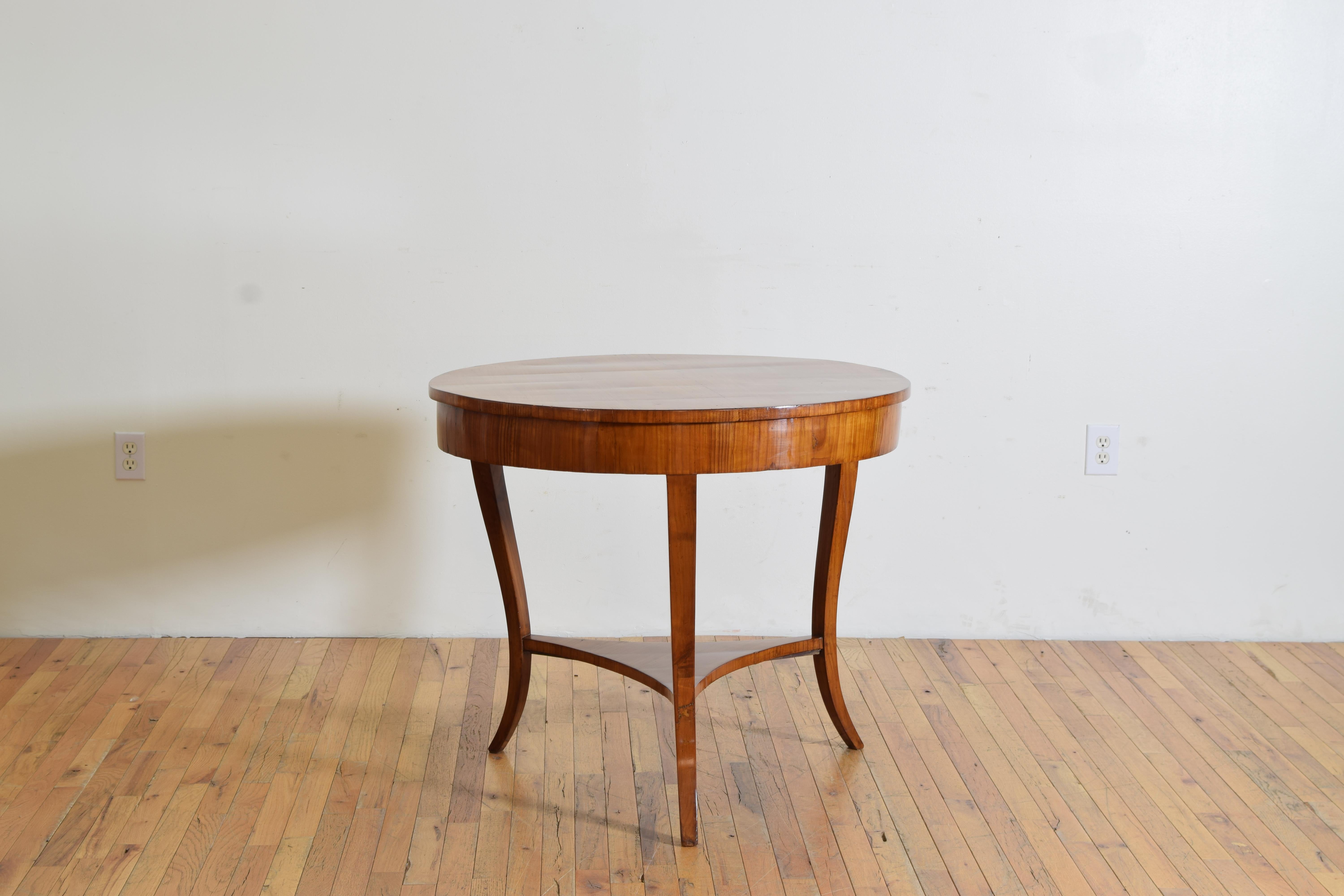 Constructed almost entirely of fruitwood veneers this center table features a round top with substantial apron raised on elegantly shaped cabriole legs joined by a shaped platform stretcher