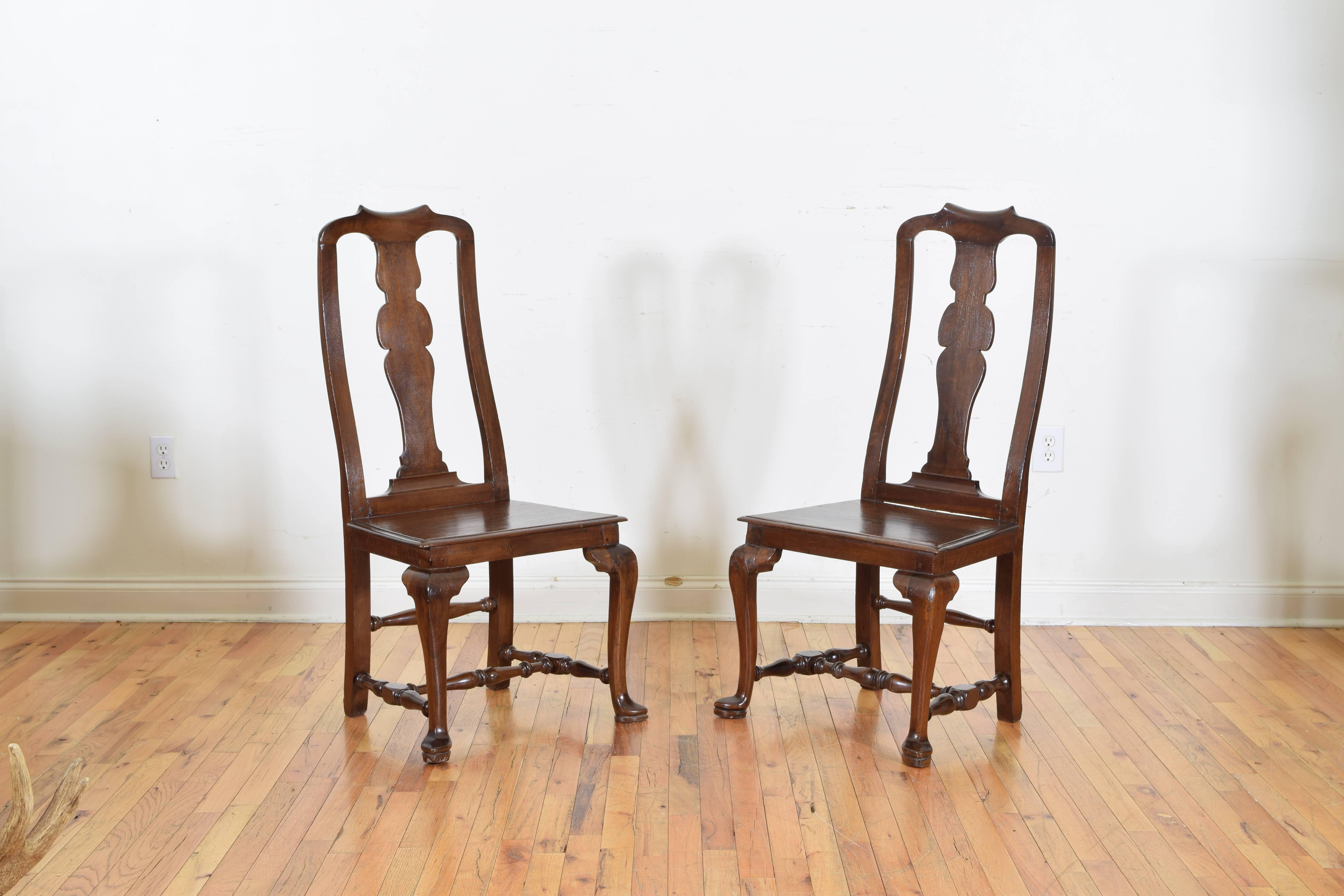 A pair of shaped walnut side chairs having a bow-shaped pierced backrests, the wooden seats supported by Queen Annes style cabriole legs with slipper feet, rear legs splayed, all joined by turned stretchers.