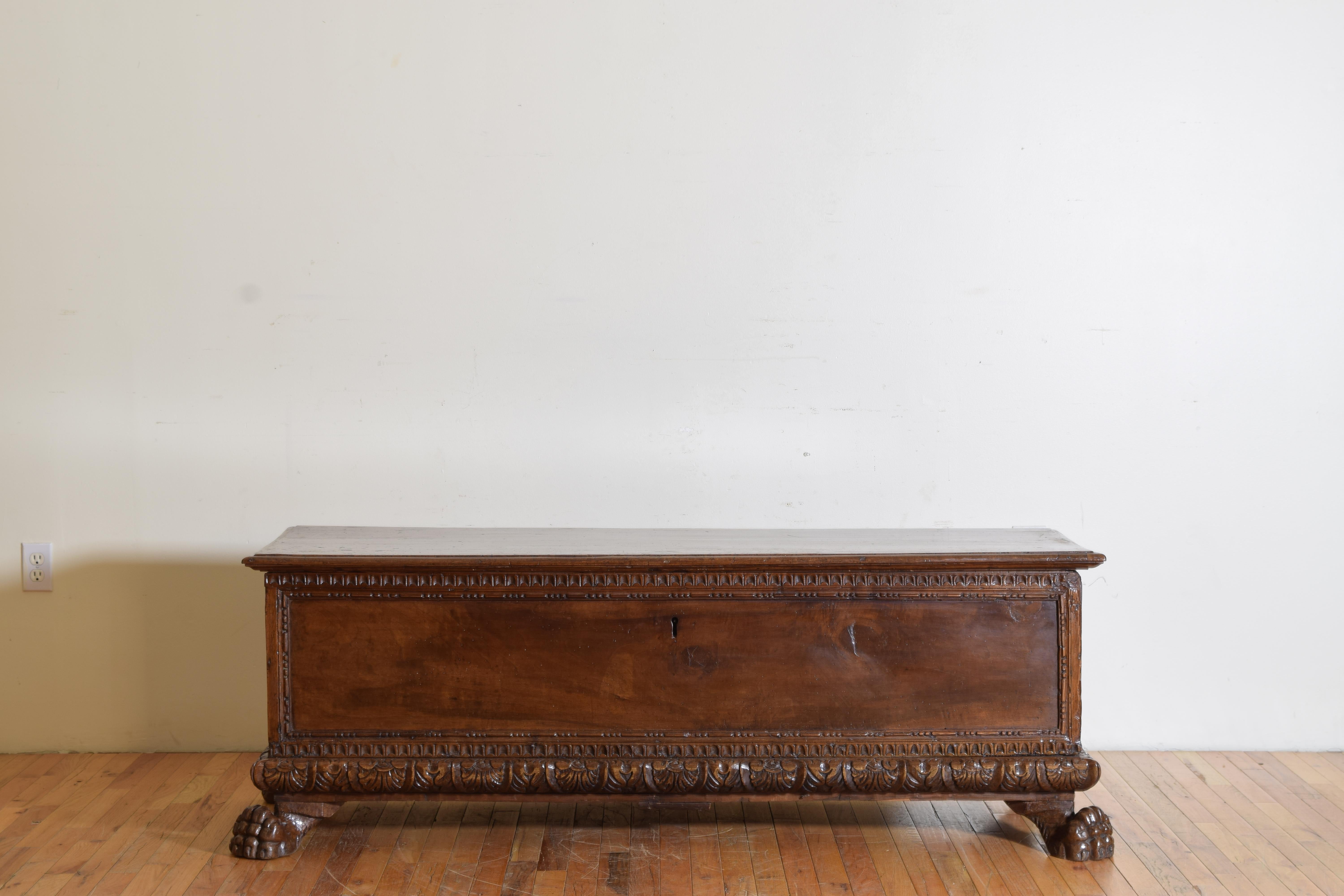 Having a hinged rectangular top, the case with upper and lower gadroon carved edge, the sides with bar and bead carved moldings, the plinth-form base with leaf carvings, the case raised on carved paw feet.