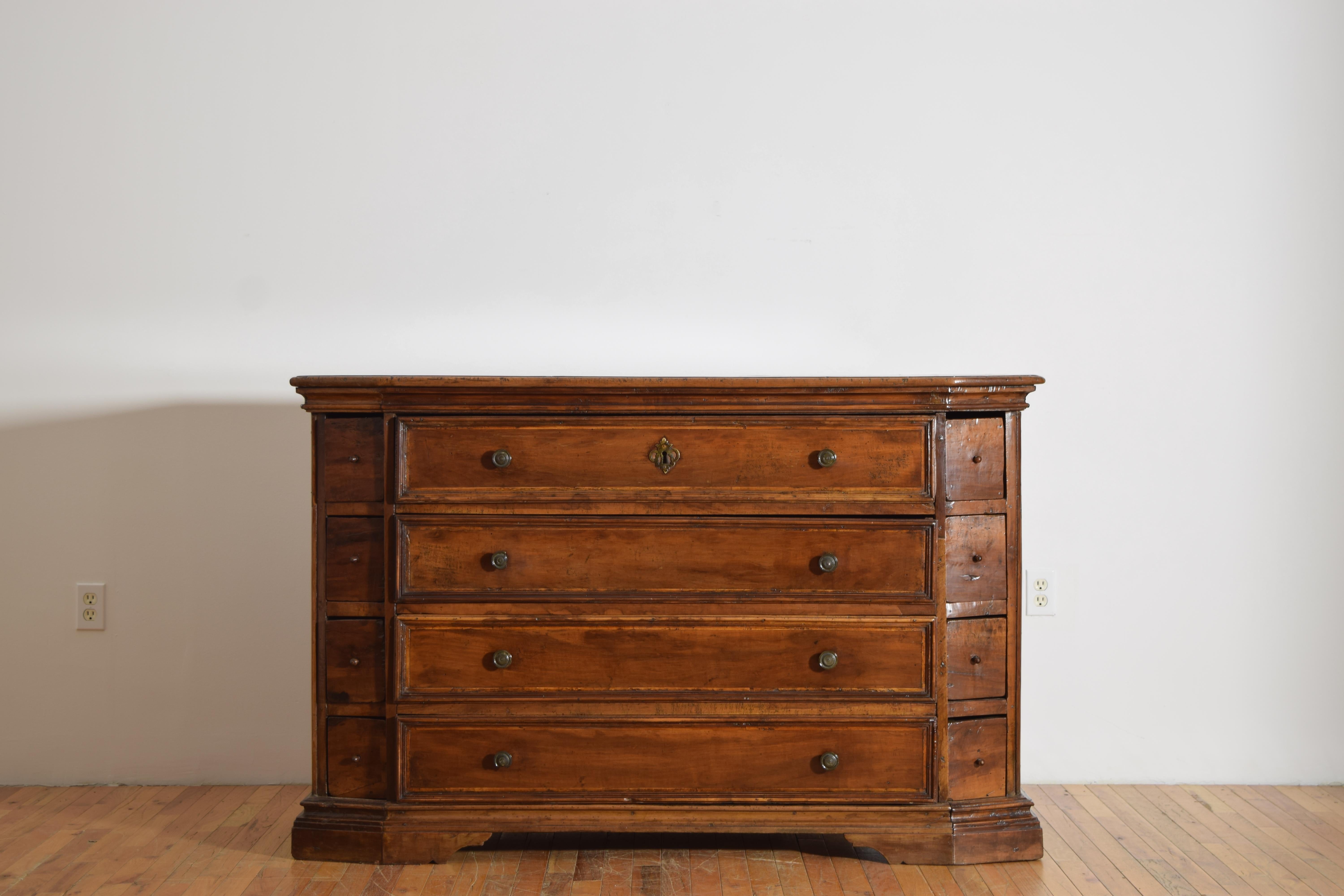 rare in form and having a rectangular top with canted corners and a molded edge above a conforming case housing 4 central drawers flanked by 4 smaller angled drawers on each side, raised on a plinth-form base