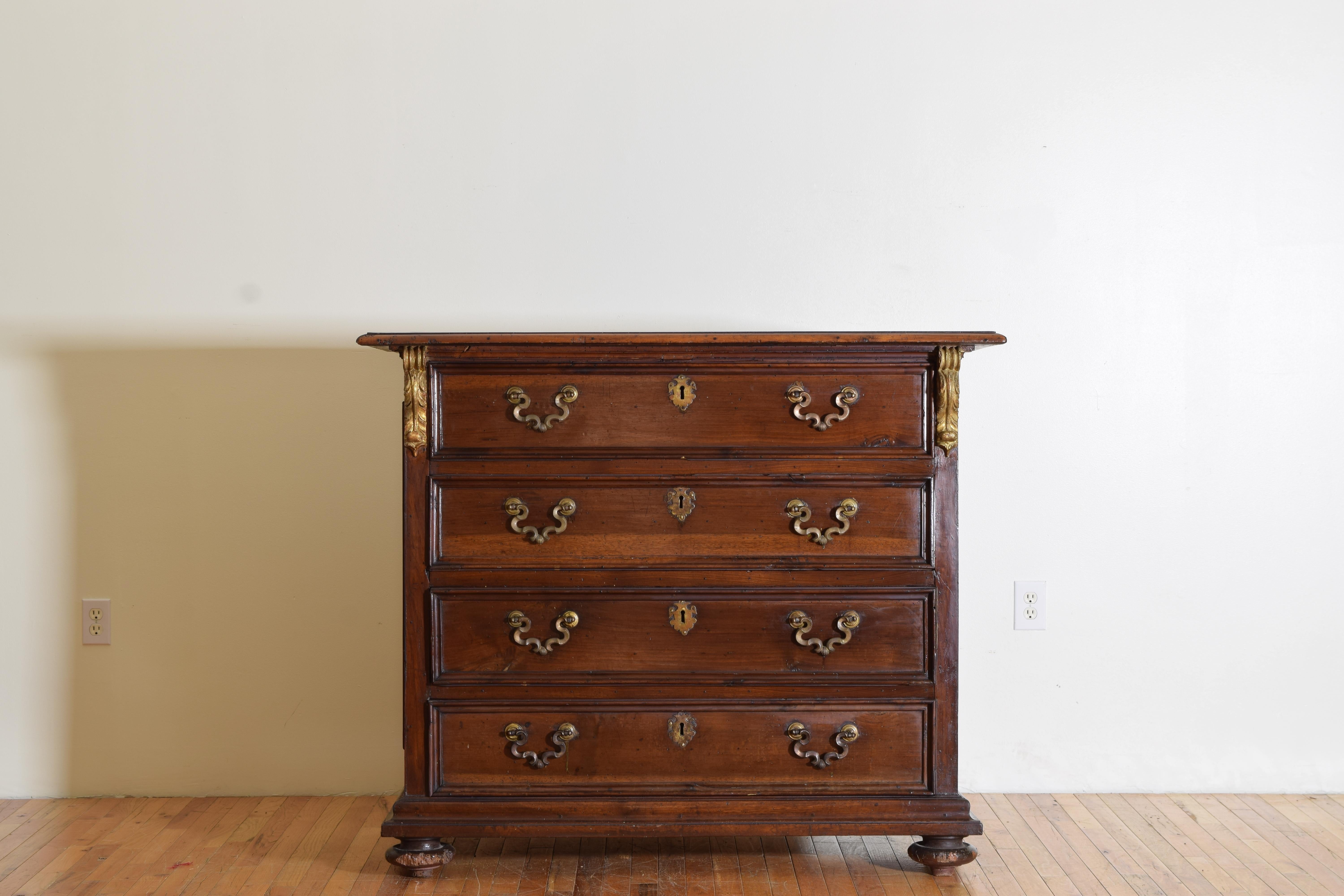 Having a rectangular top with molded edge above a conforming case housing four drawers with original bronze handles and escutcheons, giltwood leaf-form scrolls at upper front, the sides paneled, raised on original bun feet