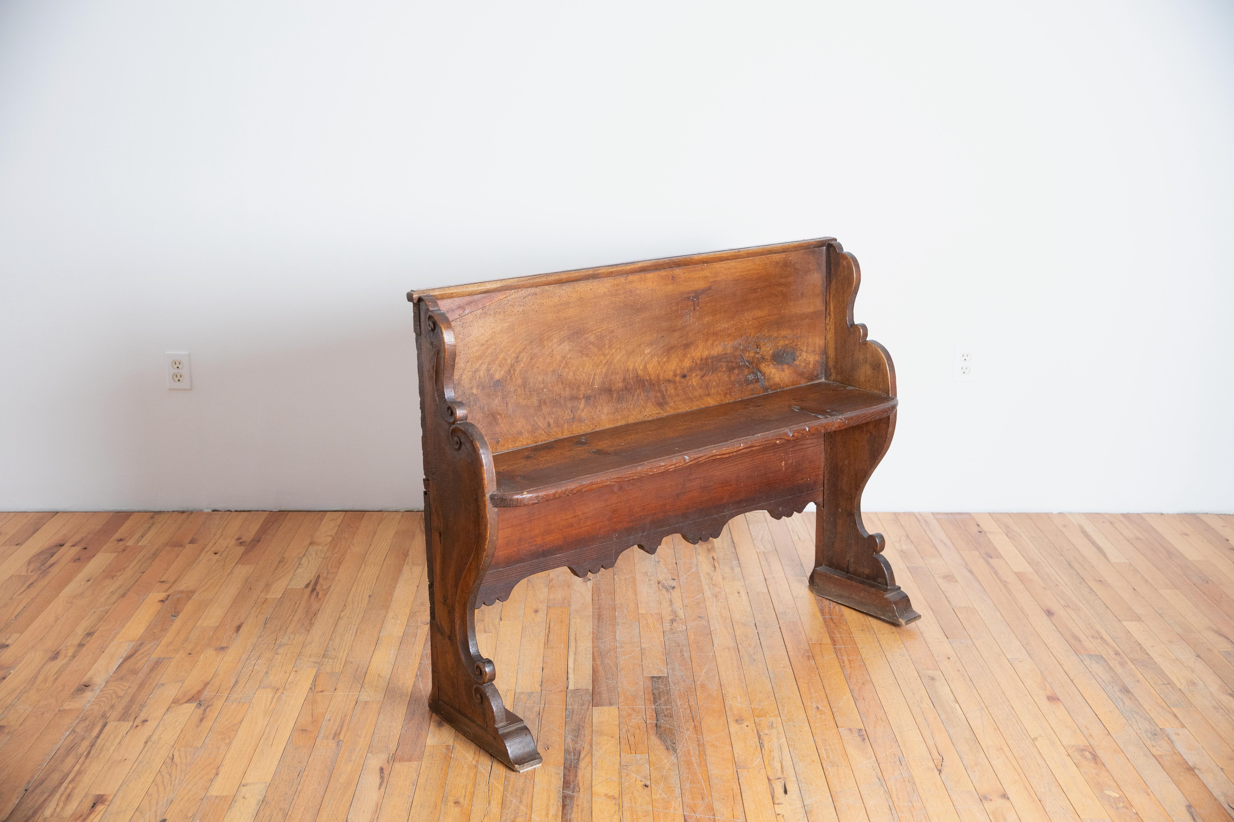 Probablement un banc provenant d'une chapelle privée, ce banc présente une assise peu profonde avec un dossier haut et des supports latéraux en forme et en volute reposant sur des pieds en console.