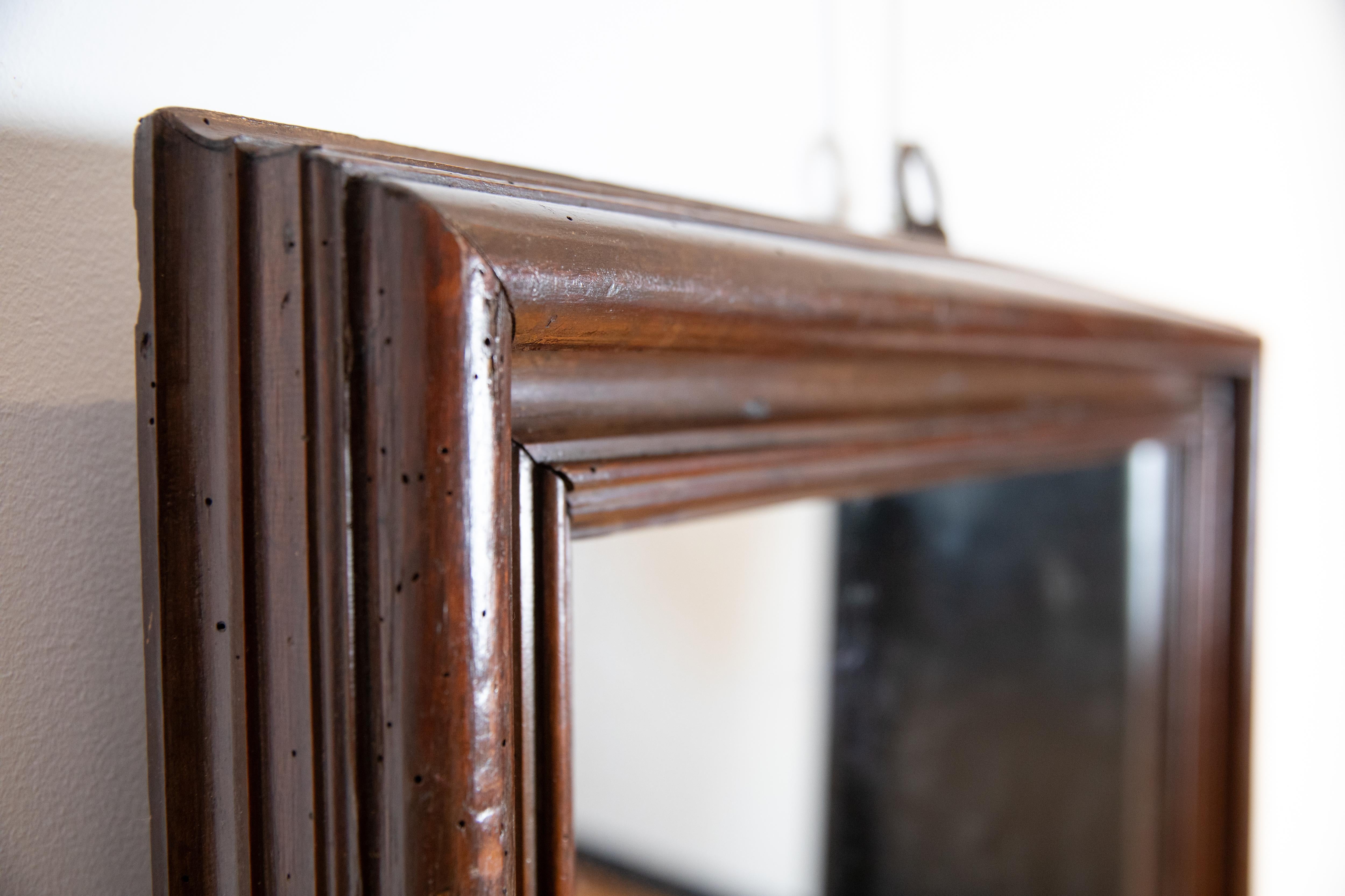 Costruita interamente in noce e con bordi modanati a più livelli, questa cornice presenta un Fleur de Lis dipinto in oro in basso a sinistra, ora con una moderna piastra a specchio.