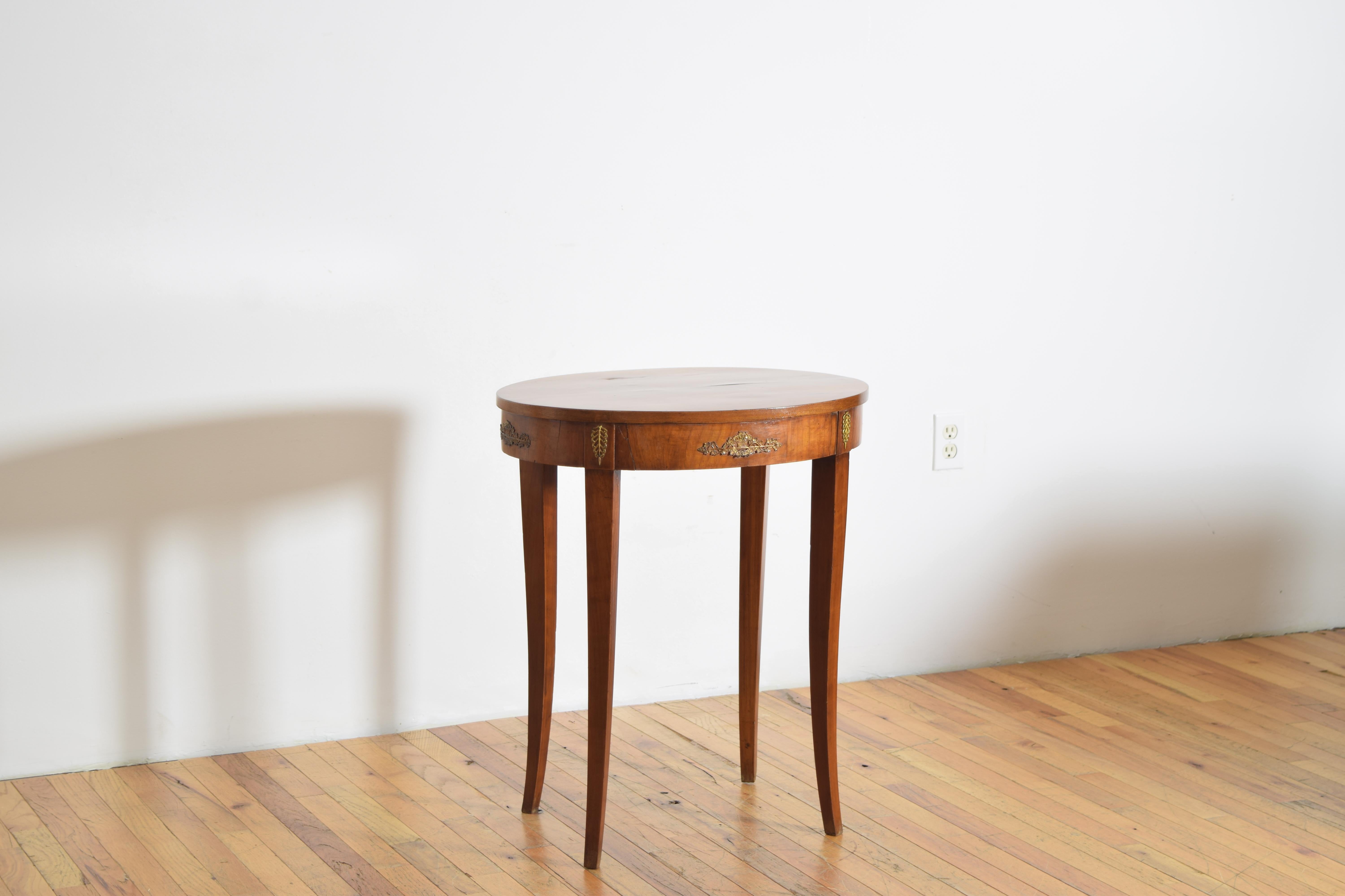 constructed entirely of solid walnut and having an oval shaped top above a conforming apron with brass mounts, the table raised on flared tapering legs