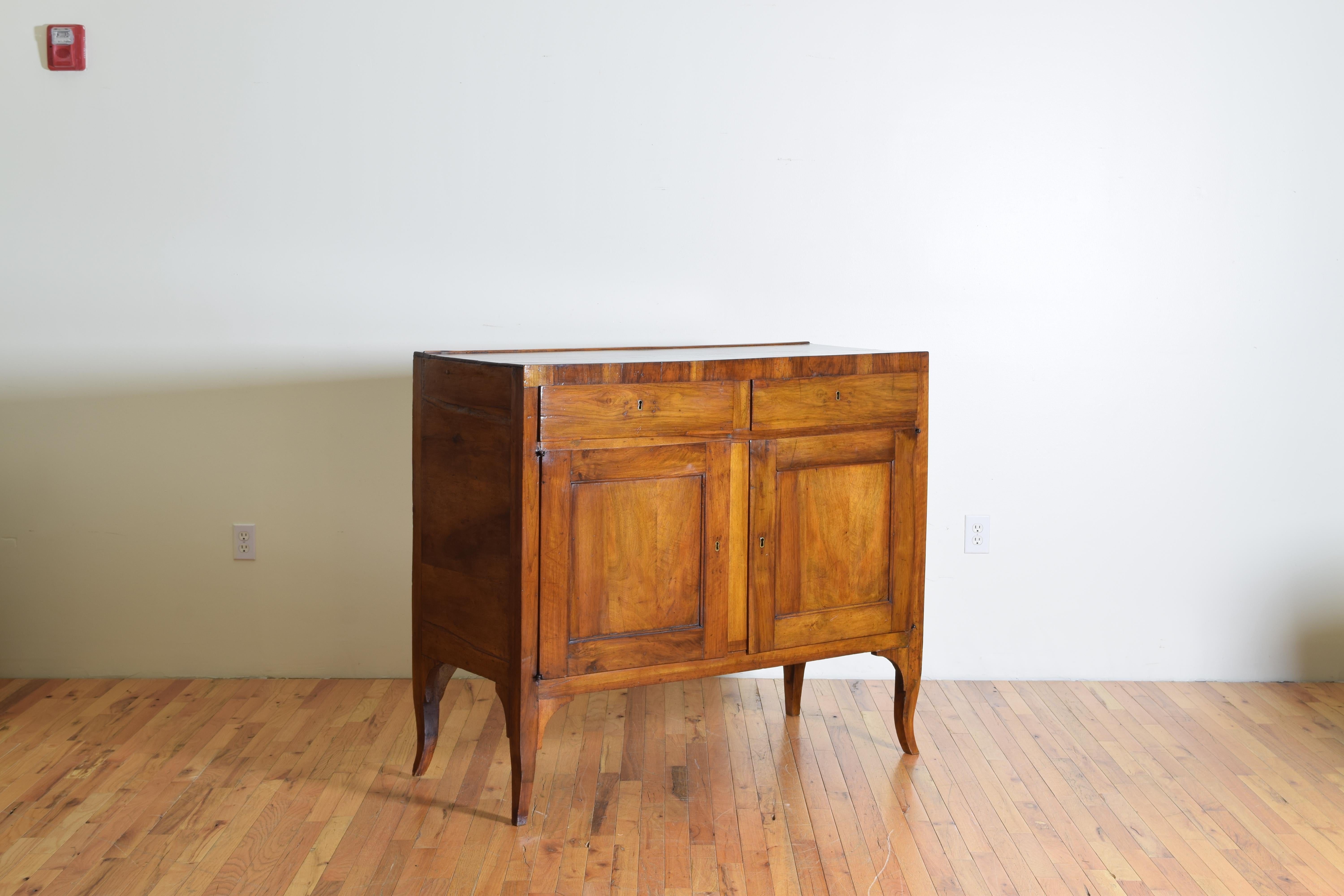 Exhibiting clean lines this credenza has a rectangular top which joins seamlessly to the case which has two drawers over two doors, the interior fitted with a centered shelf, raised on slightly curved cabriole style legs.