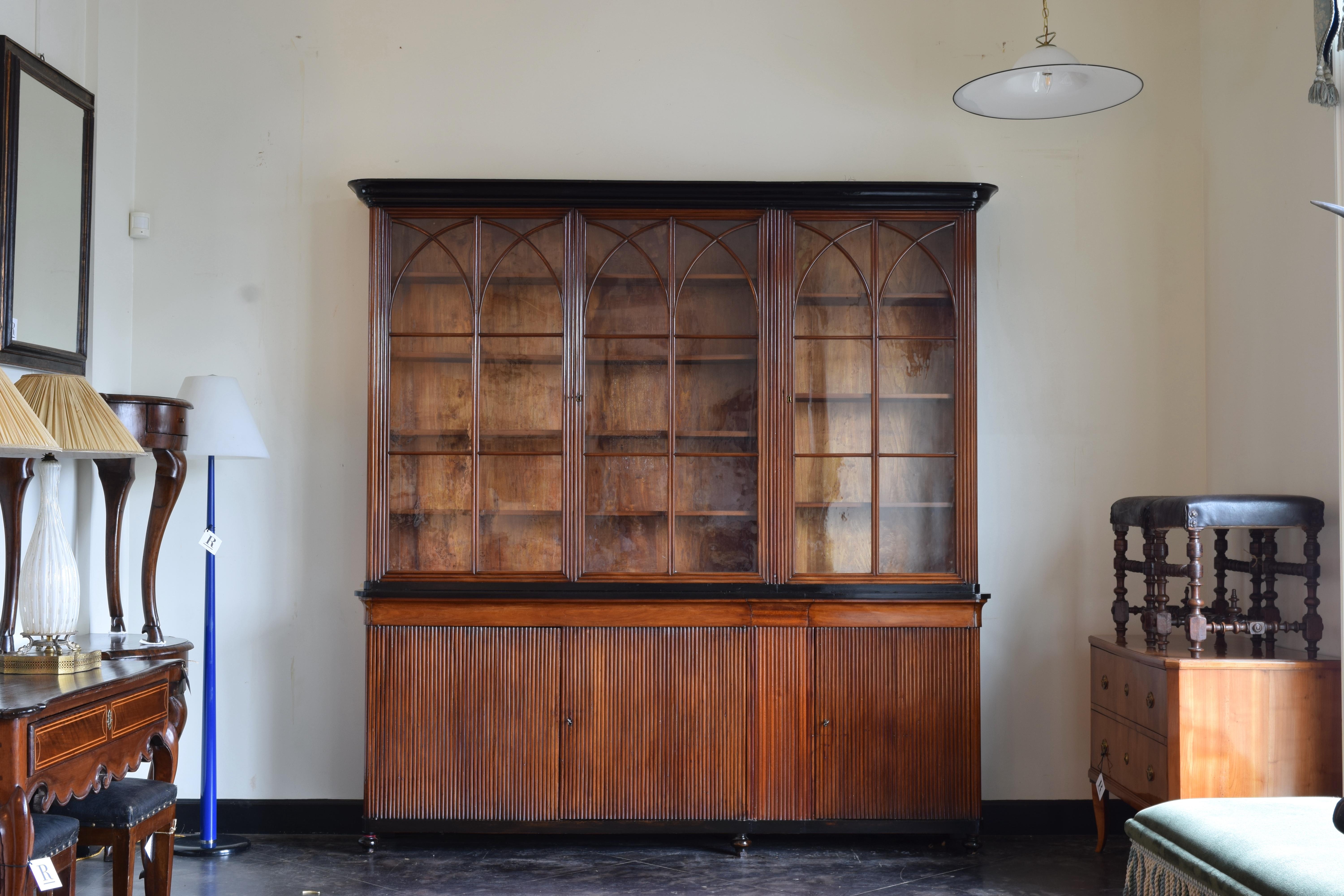 Beautifully crafted bookcase with three ebonized sections:  the crown, middle top, and lower sections and feet, the upper doors with original glass  and applied woodwork of arches, the lower sections with fluted wood, a secret section between and