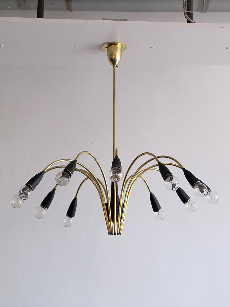 Elegant 1950s Italian twelve-light chandelier in brass with black bakelite cups and brass accents. Twelve E12 sockets per fixture, max. wattage 25w each, wired for US standards, bulbs provided as a onetime courtesy.