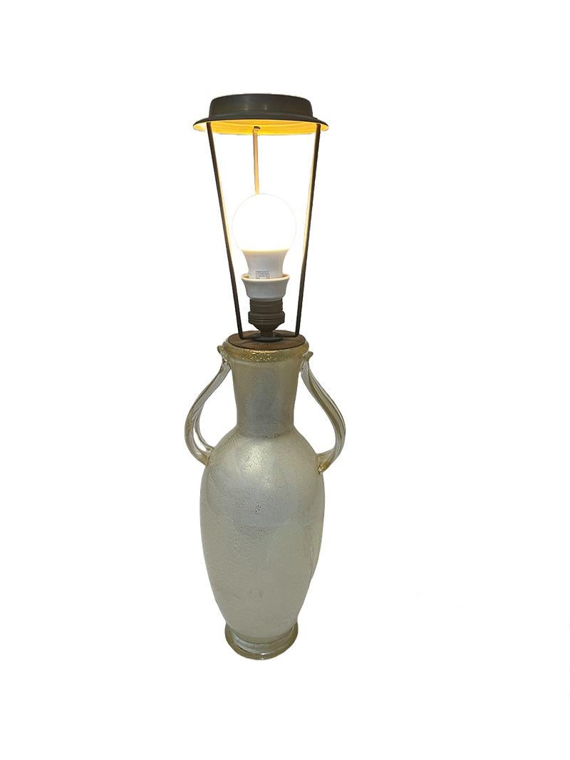 Italienische Murano-Tischlampe mit zwei Henkeln

Eine italienische Tischlampe von Murano Barovier&Toso aus der Mitte des 20. Eine Tischlampe aus mundgeblasenem weißem Glas mit Goldflocken und zwei Griffen. Die Lampenfassung ist aus Porzellan