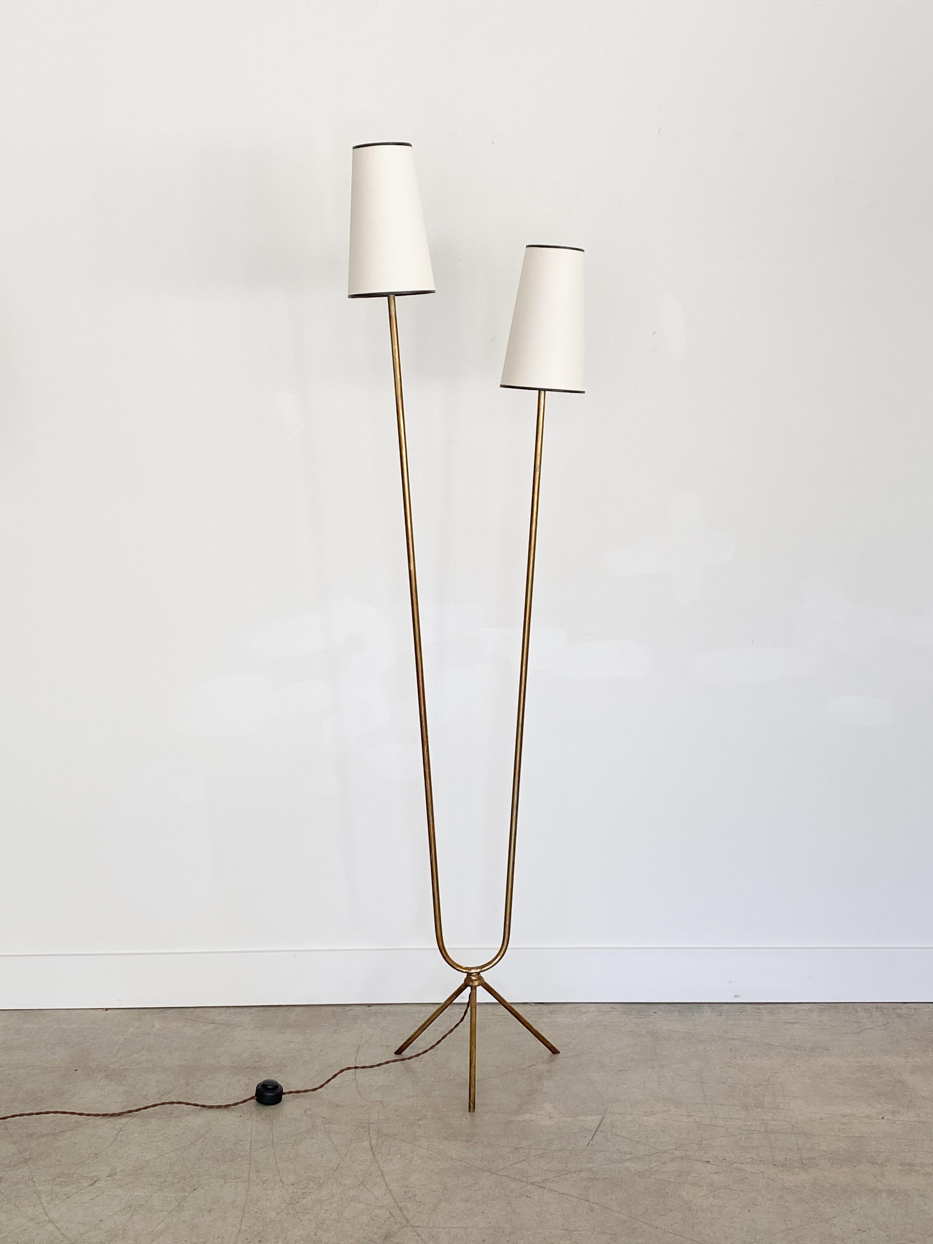 Vintage 1950s brass floor lamp from Italy. Brass tripod base with U-shaped long brass stems each with single sockets. Newly re-wired and new paper shades. Original brass has great patina and age.