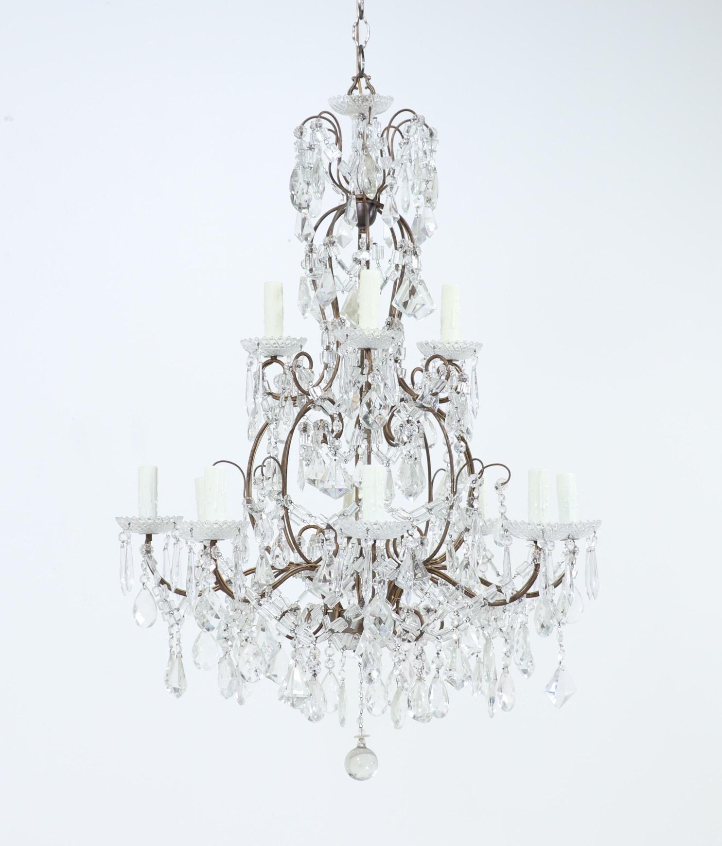 Glamorous, 1940s Italian gilt-iron and crystal two-tier chandelier.

The chandelier features a shapely, scrolled wrought iron frame with gilt paint finish and an abundance of crystal decorations. 

The chandelier is wired and in working condition,