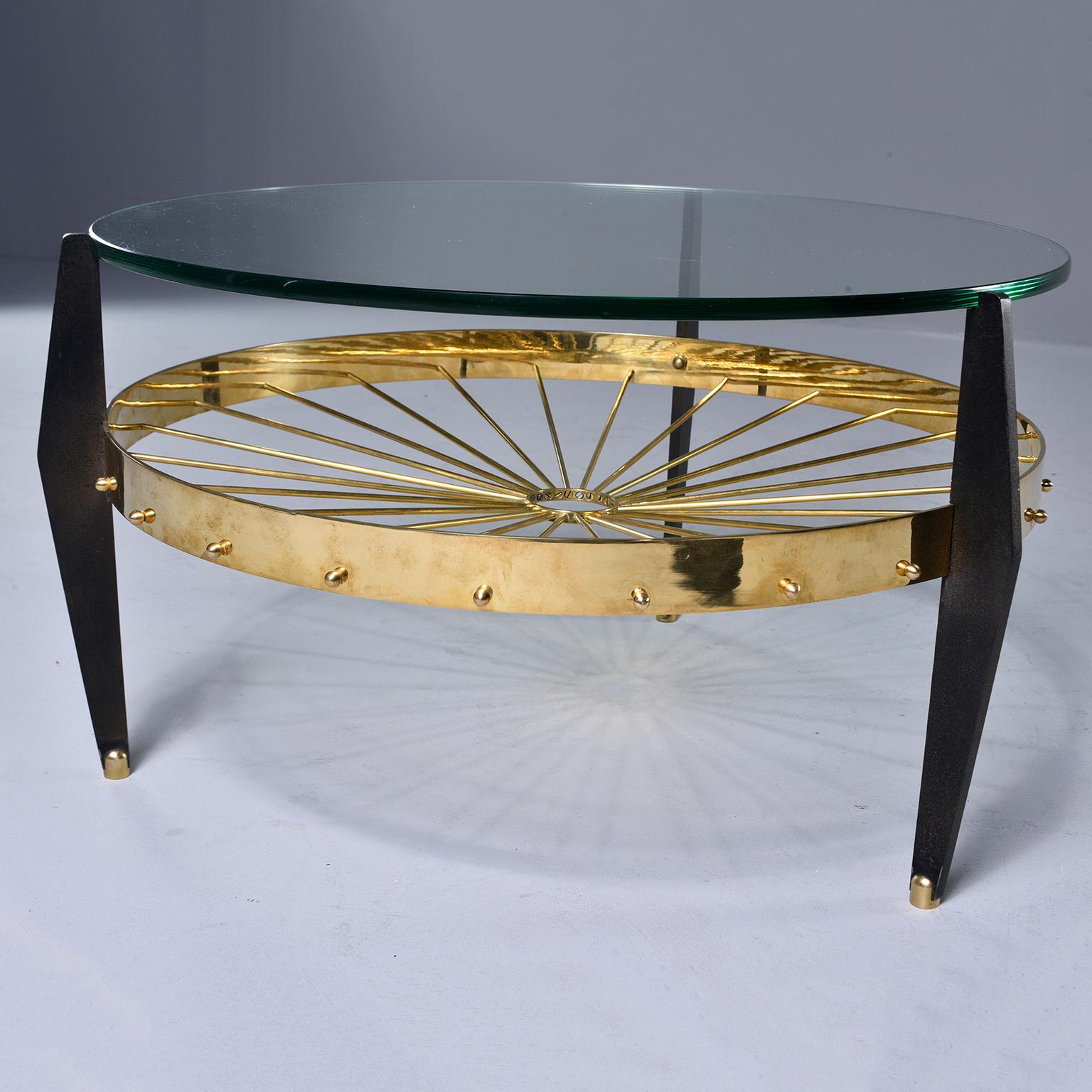Unusual circa 1970s side table has a brass base with slender spokes and black wood legs with brass capped feet and a heavy glass top.