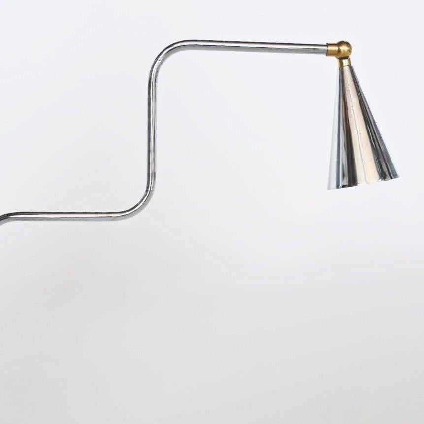 Beautiful delicate chrome plated sconce with brass accents by Disegno Luce. Italy c. 1980's. Pivot arm with a unique double curved extension. Conical chrome plated shade with rotating brass connection to arm. Marked Disegno Luce at backplate.