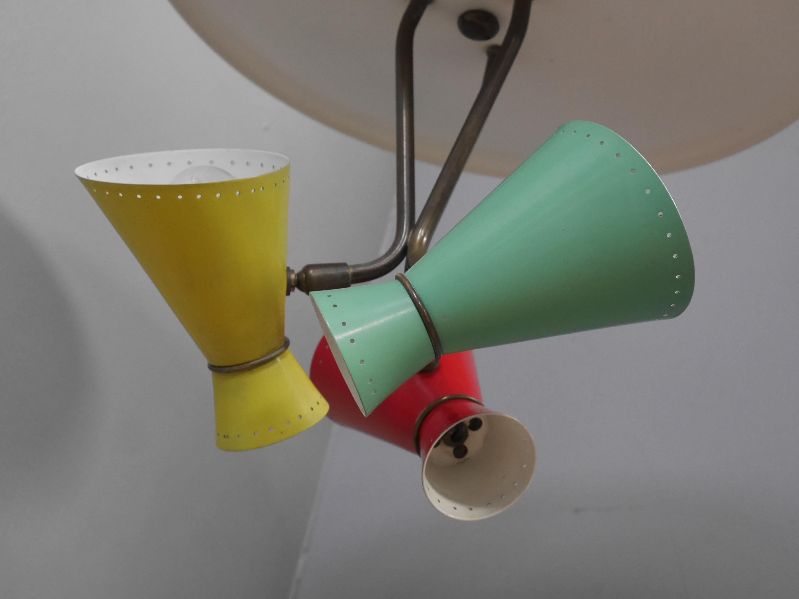 A vintage Italian pendant light c1950.
A phenomenal mid century Italian pendant light, the large white reflector supporting three patinated brass arms terminating in articulated ball joints supporting multicoloured 'diablo' shades. The red, yellow &